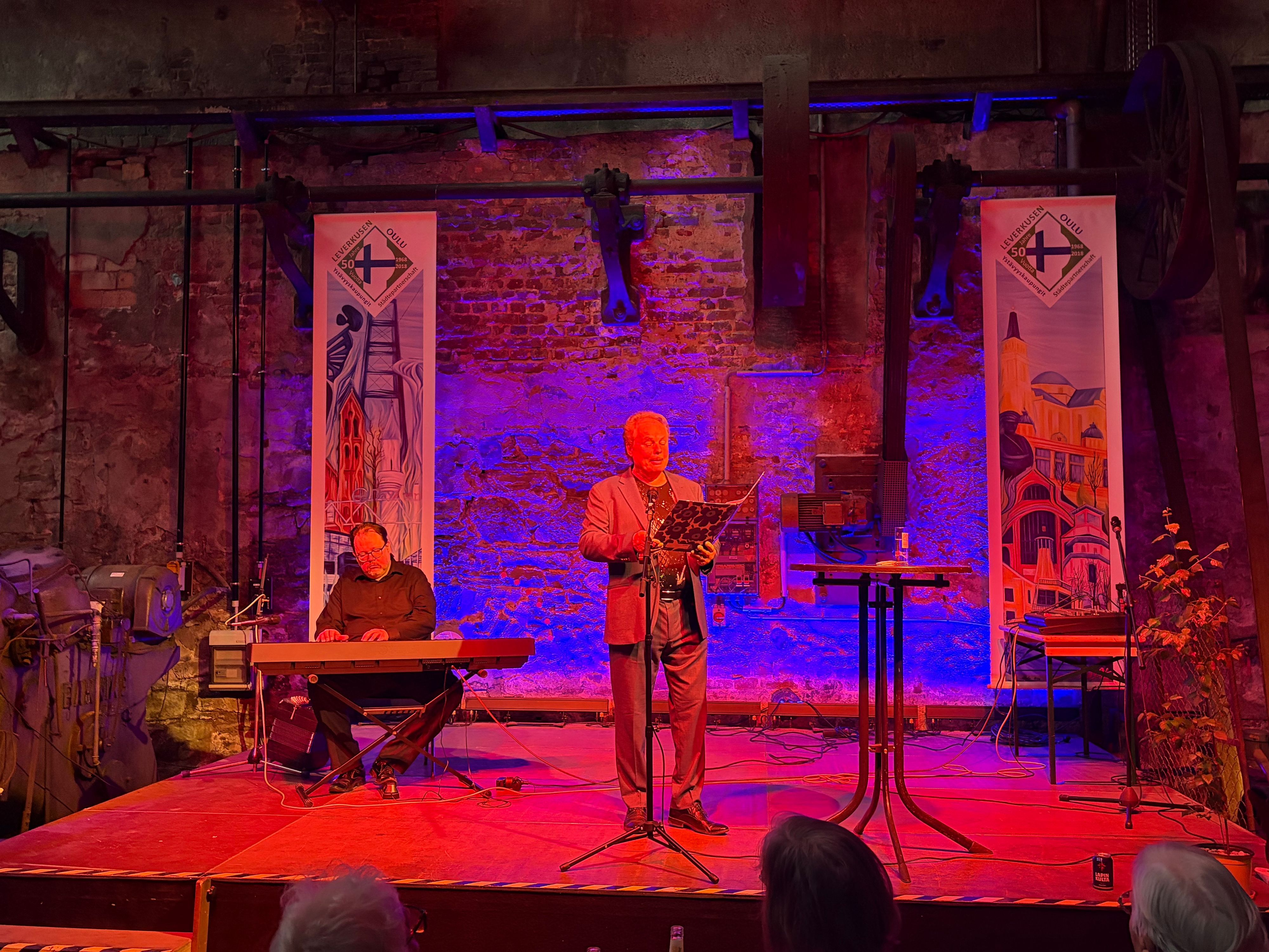 Zwei Männer stehen auf einer Bühne und musizieren.
