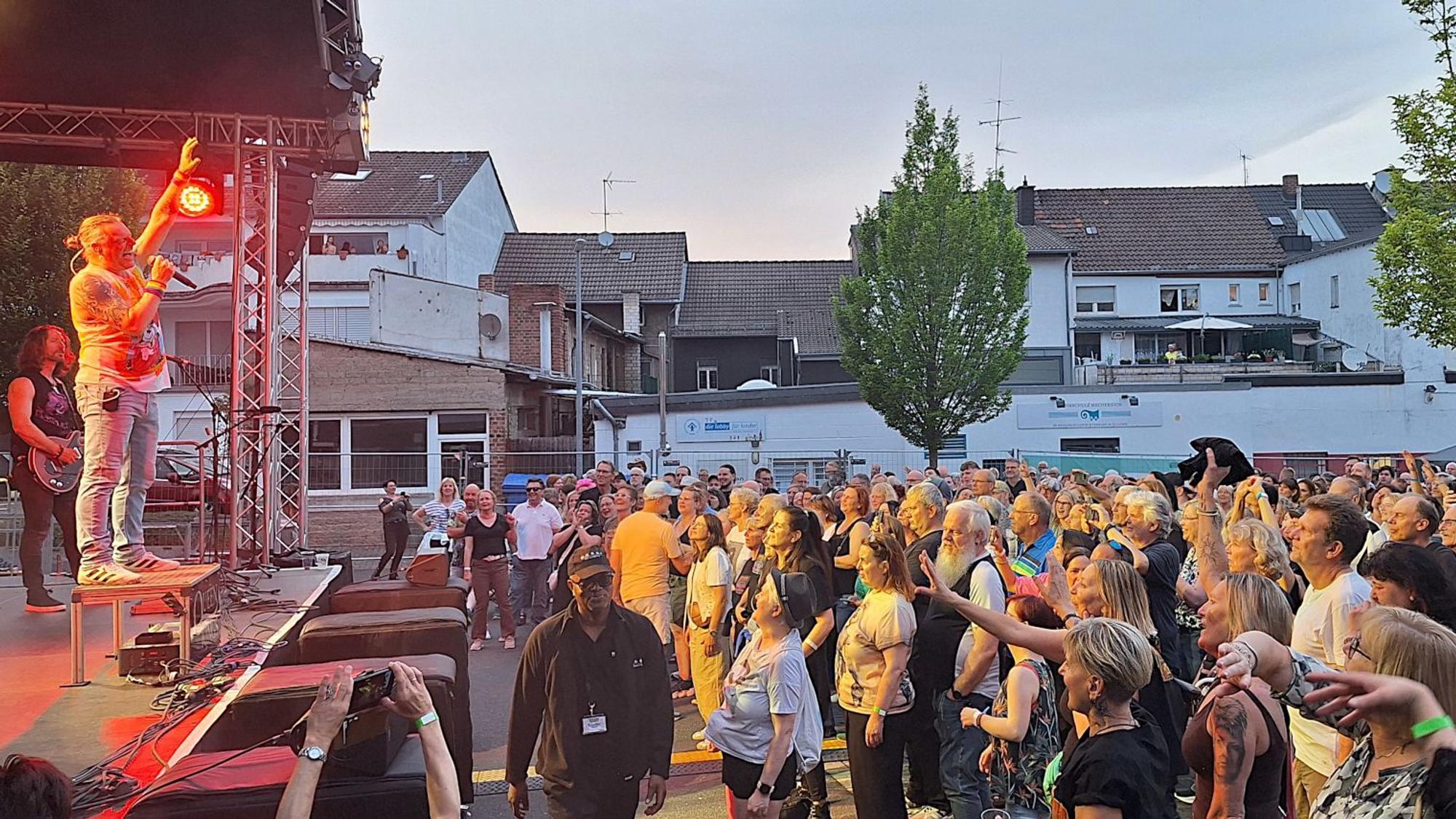 Das Foto zeigt die Band beim Auftritt und feiernde Fans vor der Bühne.