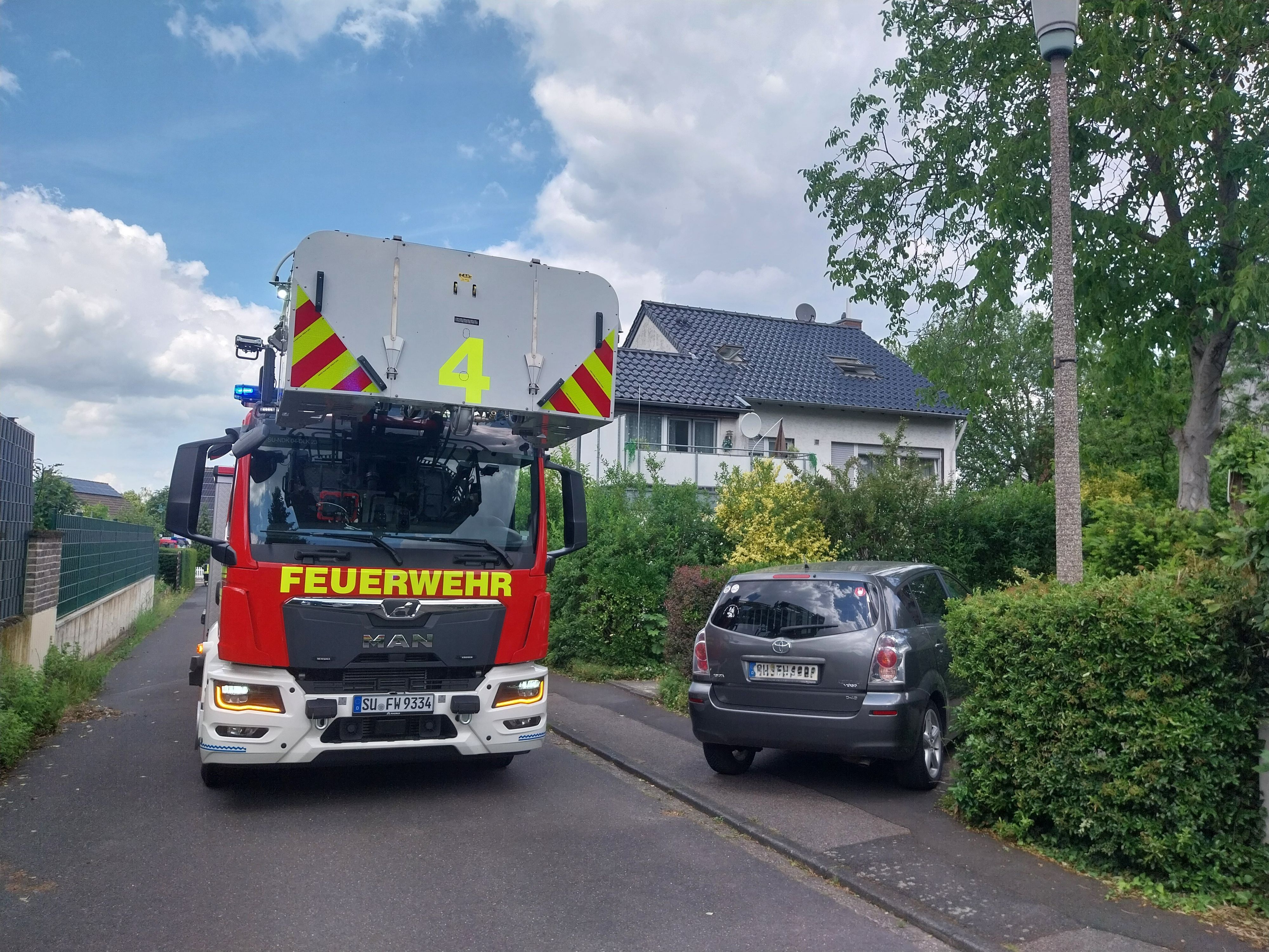 Ein Drehleiterfahrzeug der Feuerwehr steht in einer Wohnstraße.