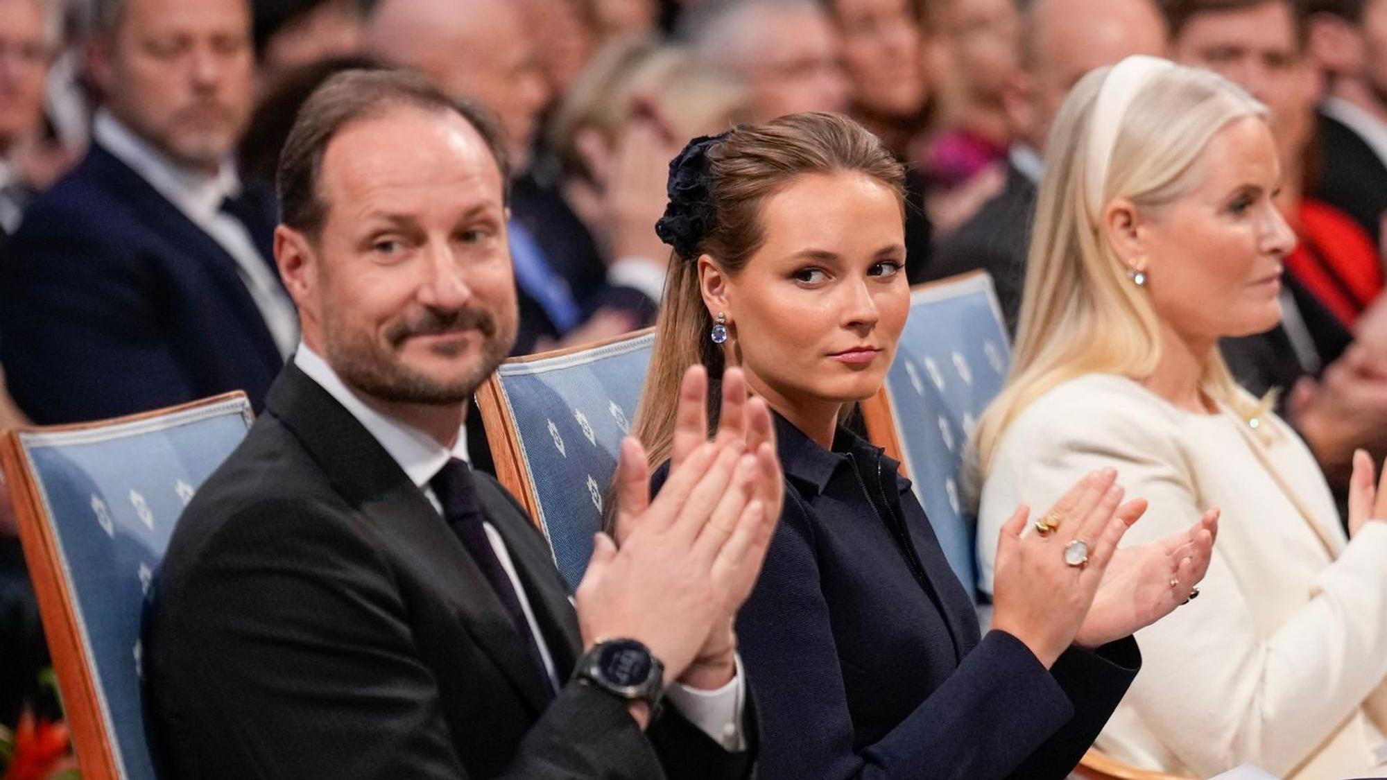 König Haakon und Kronprinzessin Ingrid Alexandra sitzen und klatschen.