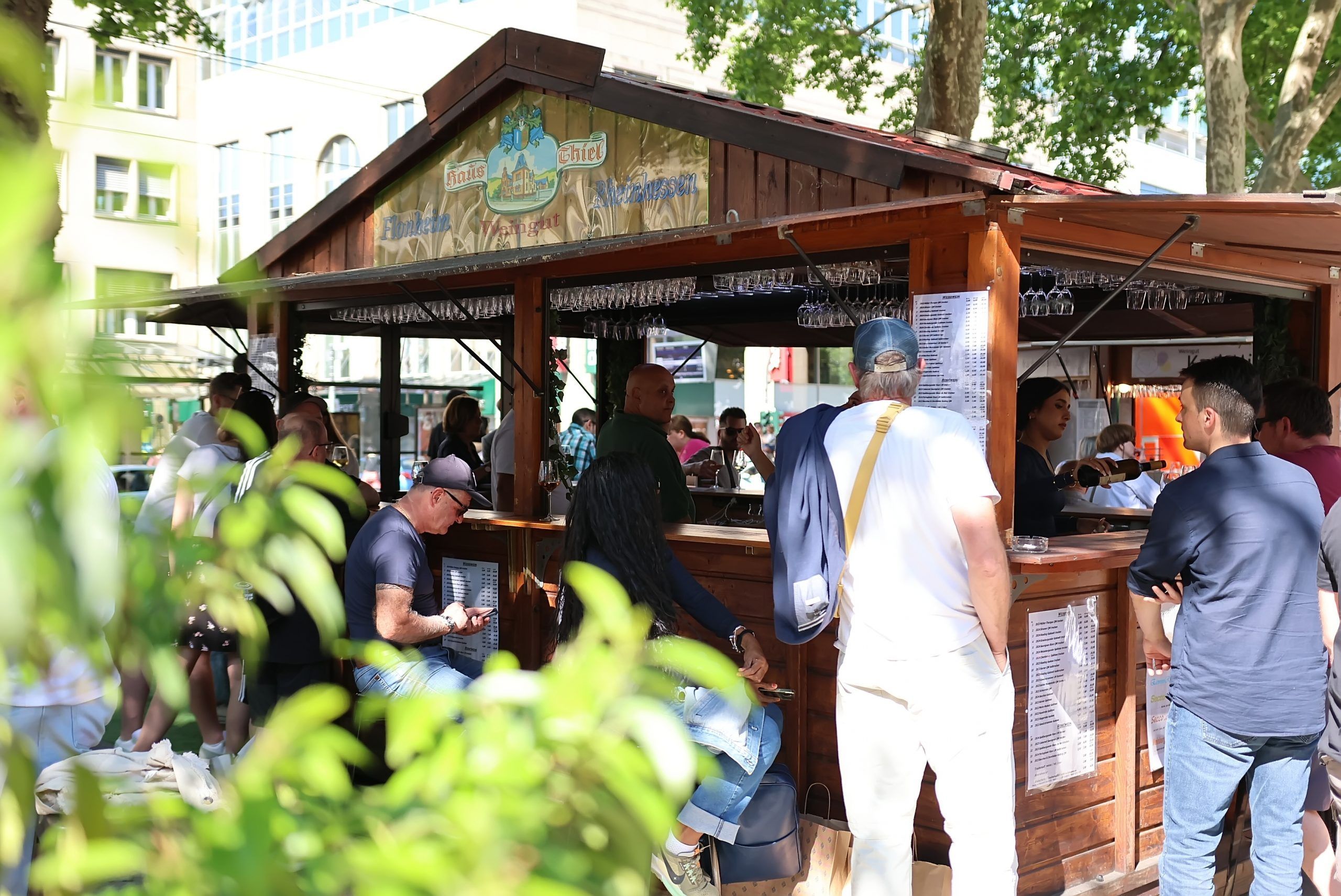 Leute stehen um einen Weinstand auf dem Kölner Neumarkt herum.