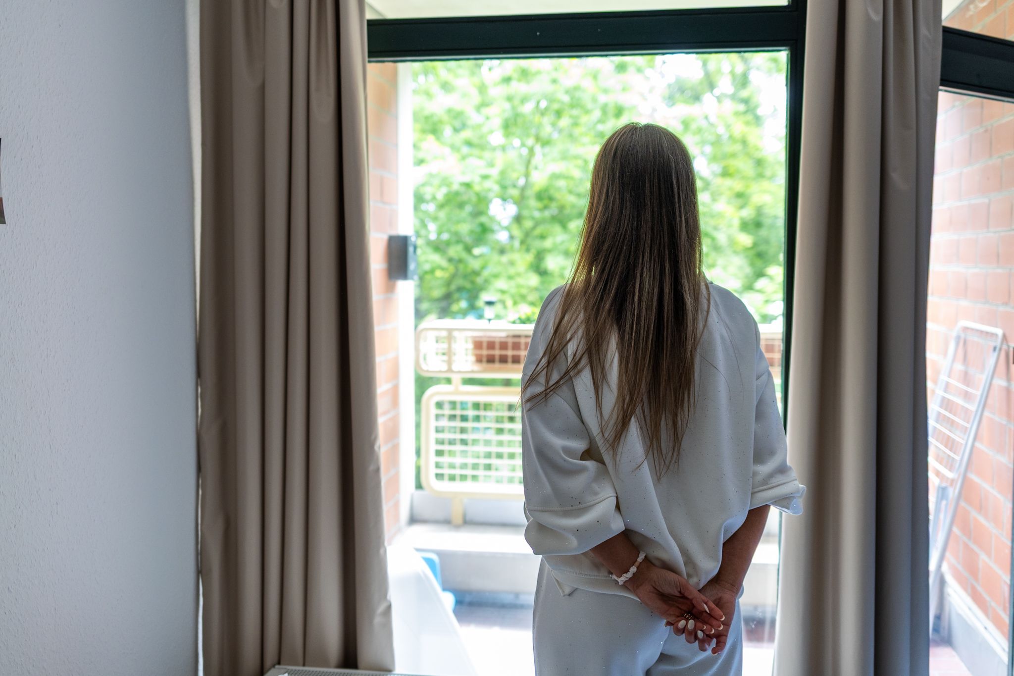 Eine Frau von hinten abgebildet vor einem Fenster.