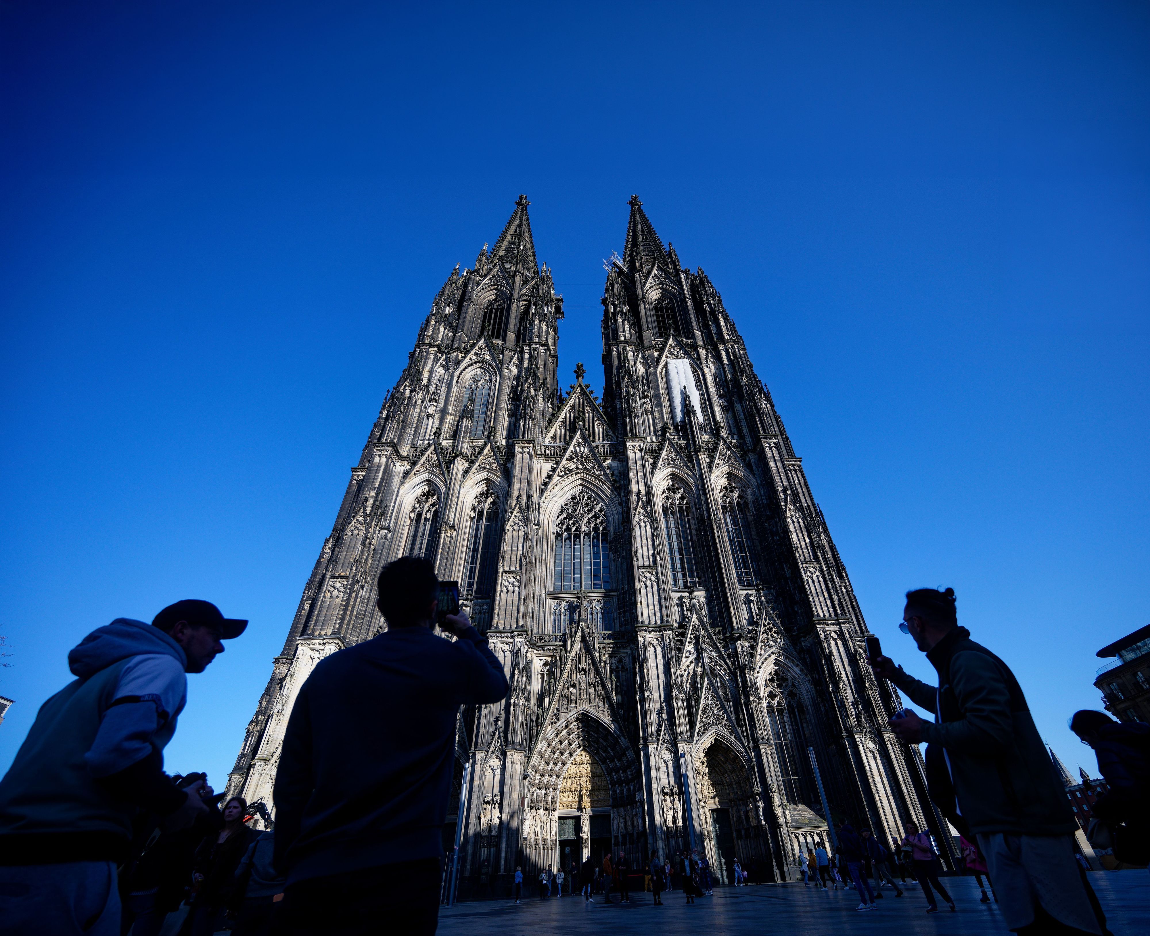 ARCHIV - 05.03.2026, Nordrhein-Westfalen, Köln: Touristen fotografieren den Kölner Dom. Der Kölner Dom wird Touristen in Zukunft Eintritt kosten. Damit sollen die gestiegenen Kosten für Pflege, Schutz und den laufenden Betrieb des Doms gedeckt werden, wie das Domkapitel mitteilte. (zu dpa: «Von Ablehnung bis Verständnis - Promis zum Dom-Eintritt») Foto: Henning Kaiser/dpa +++ dpa-Bildfunk +++