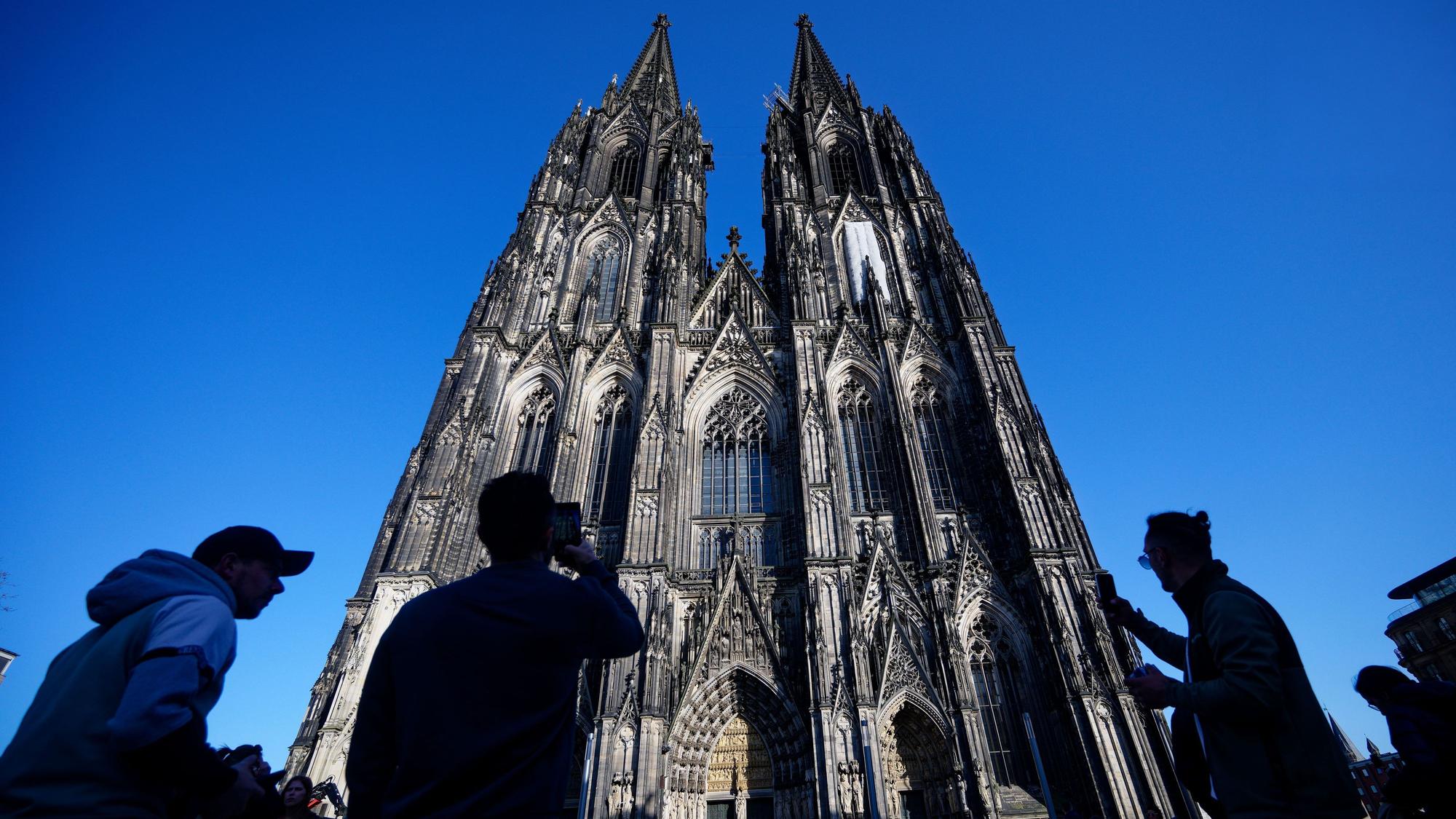ARCHIV - 05.03.2026, Nordrhein-Westfalen, Köln: Touristen fotografieren den Kölner Dom. Der Kölner Dom wird Touristen in Zukunft Eintritt kosten. Damit sollen die gestiegenen Kosten für Pflege, Schutz und den laufenden Betrieb des Doms gedeckt werden, wie das Domkapitel mitteilte. (zu dpa: «Von Ablehnung bis Verständnis - Promis zum Dom-Eintritt») Foto: Henning Kaiser/dpa +++ dpa-Bildfunk +++