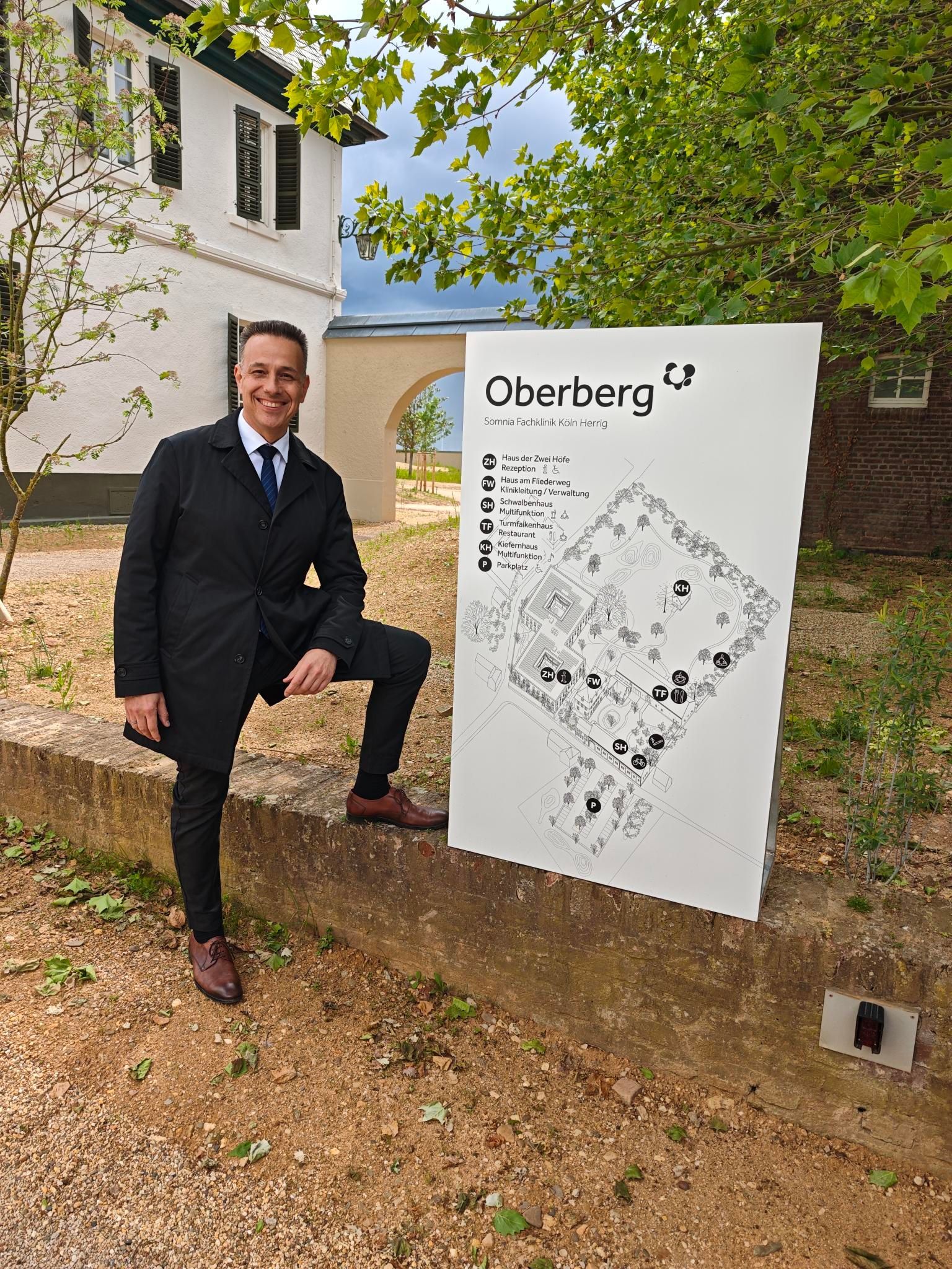 Ein Mann im Anzug steht neben einem Schild.
