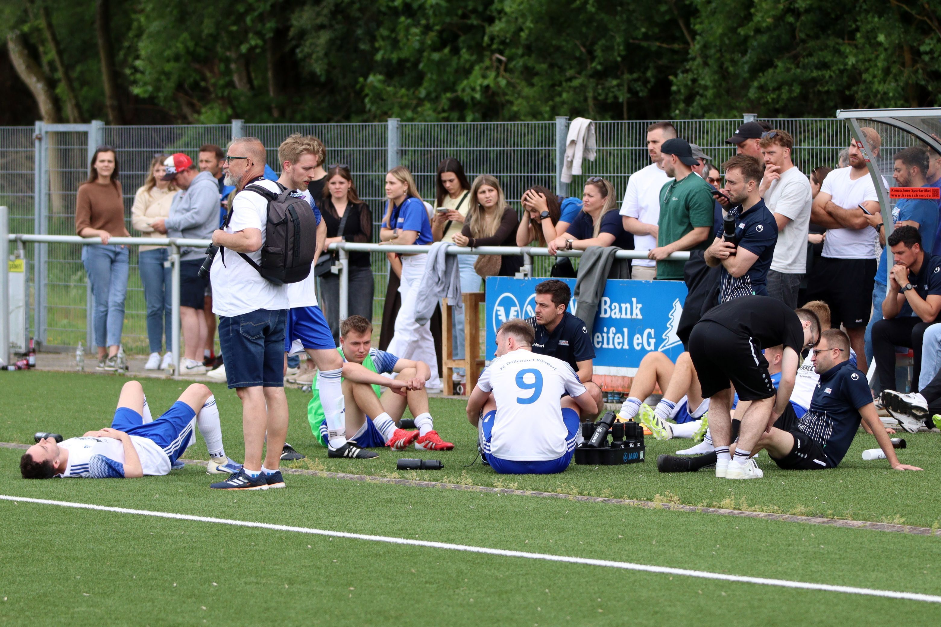 Spieler des FC Dollendorf-Ripsdorf liegen und sitzen enttäuscht auf dem Kunstrasen.