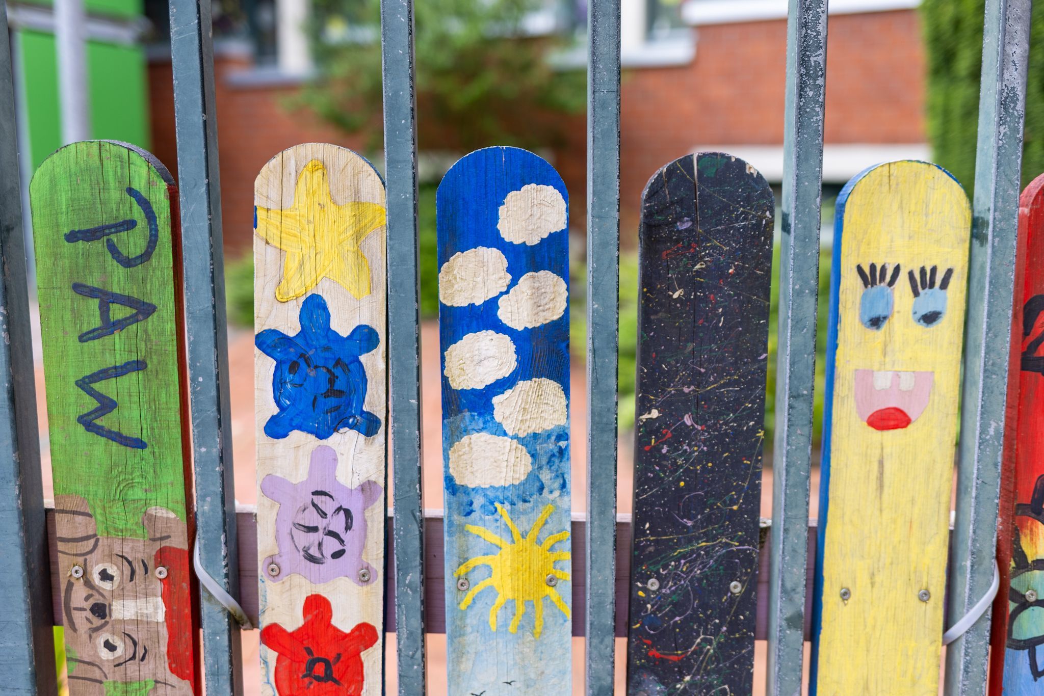 Ein grauer Zaun mit bunt angestrichenen Holzbalken.