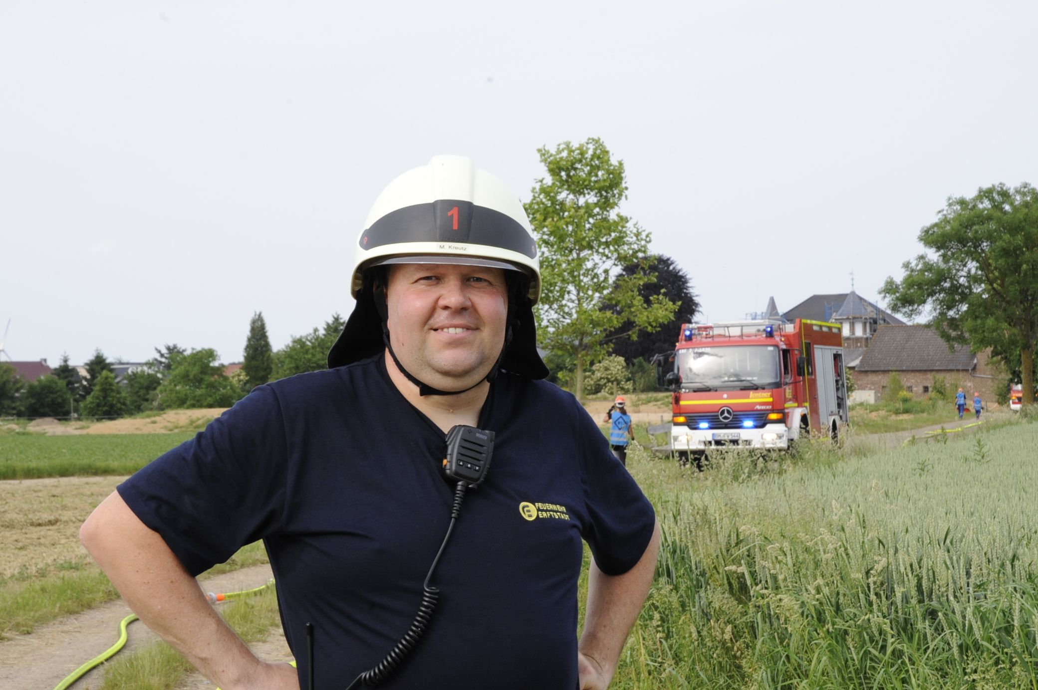 Ein Mann in Feuerwehrhelm steht vor einem Einsatzfahrzeug.