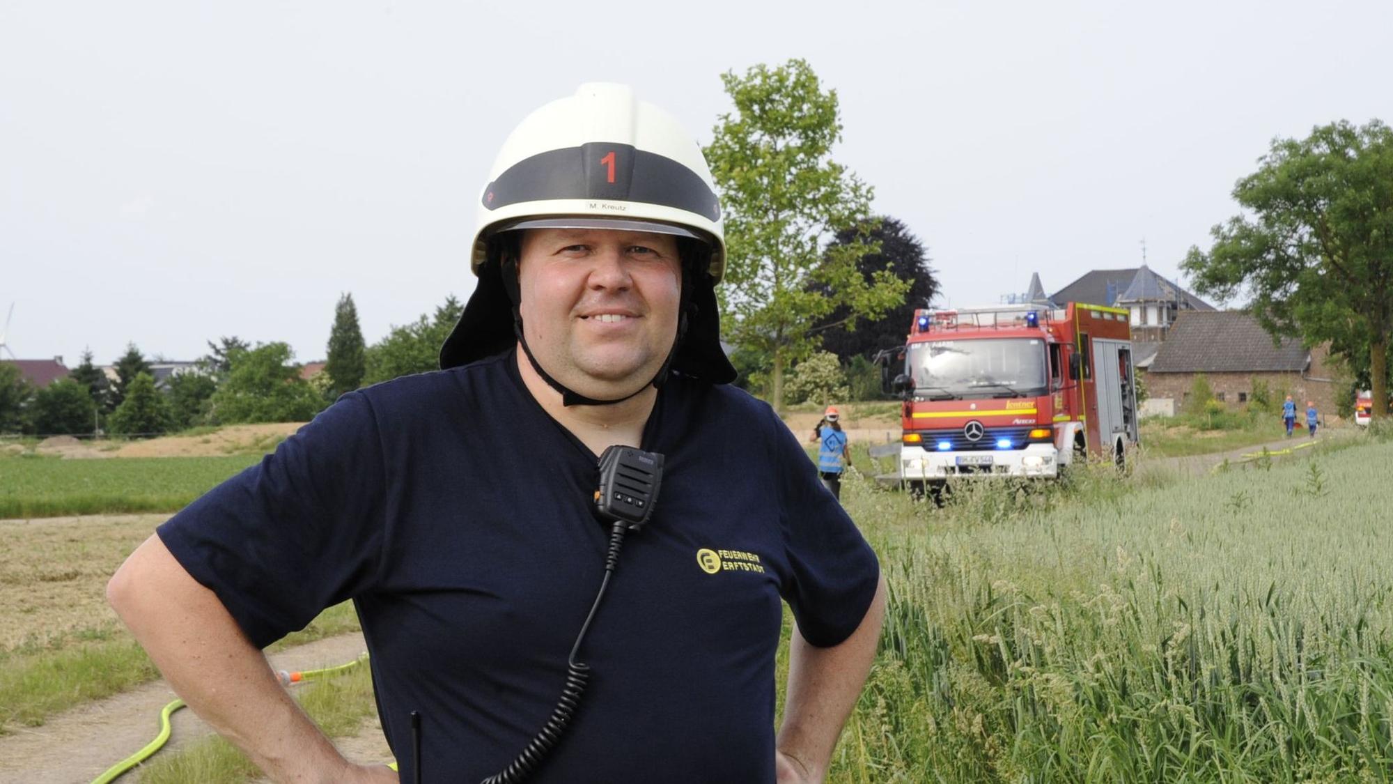 Ein Mann in Feuerwehrhelm steht vor einem Einsatzfahrzeug.