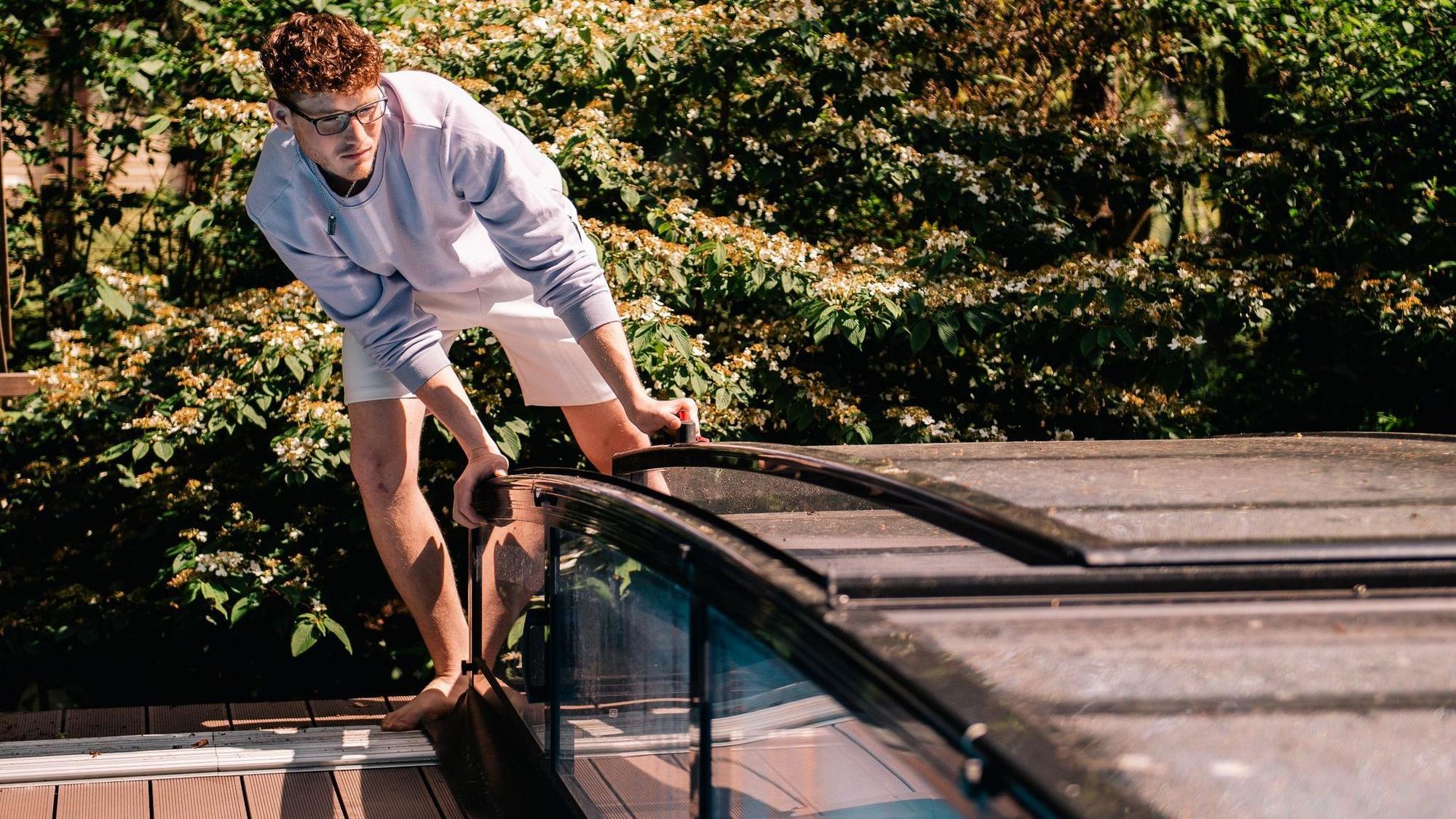Ein Jugendlicher öffnet eine Poolabdeckung