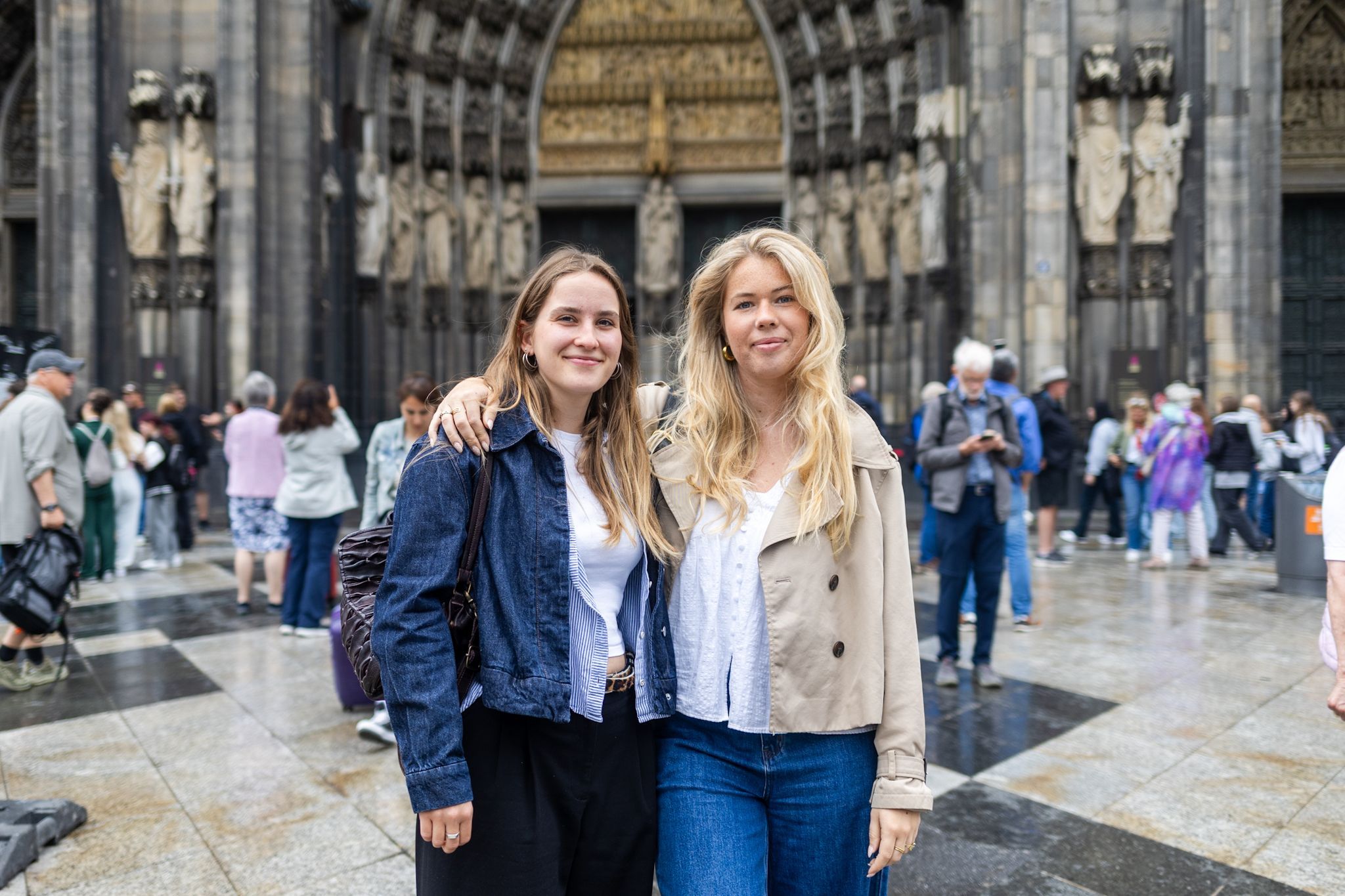Zwei Frauen stehen Arm in Arm vor einer Menschenmasse am Dom