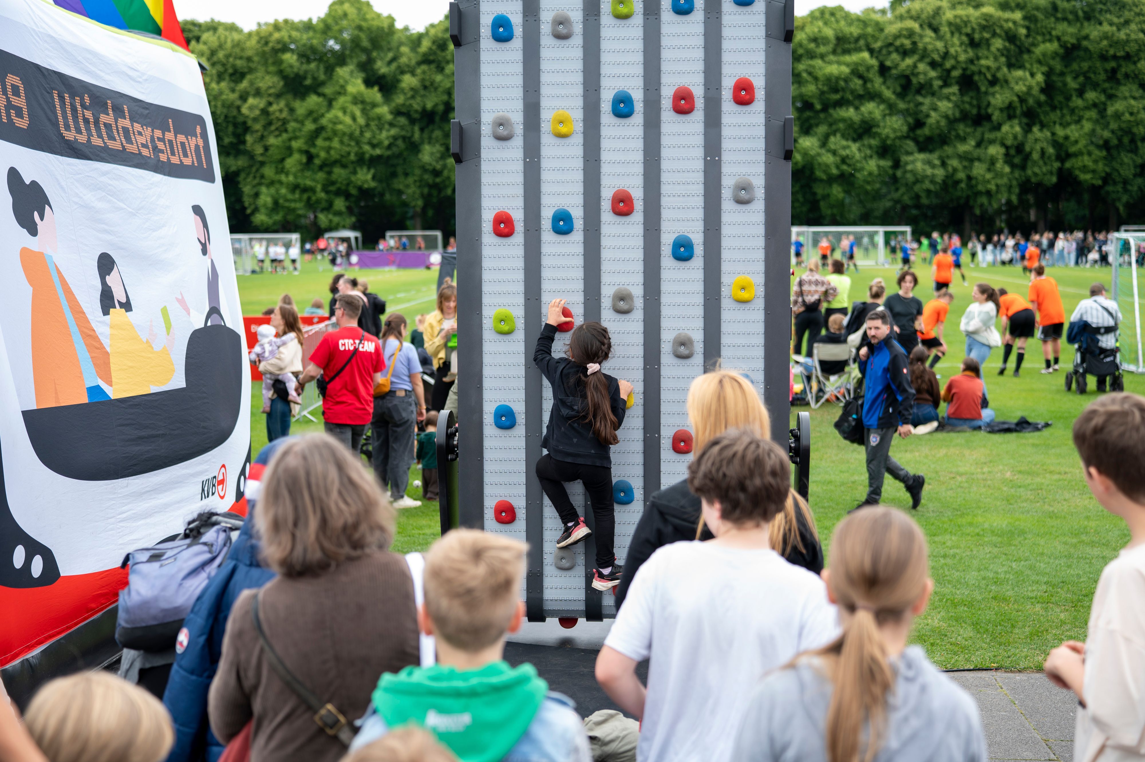 Ein Kind an einer Kletterwand, dahinter eine Fußballwiese - beim Come Together Cup.