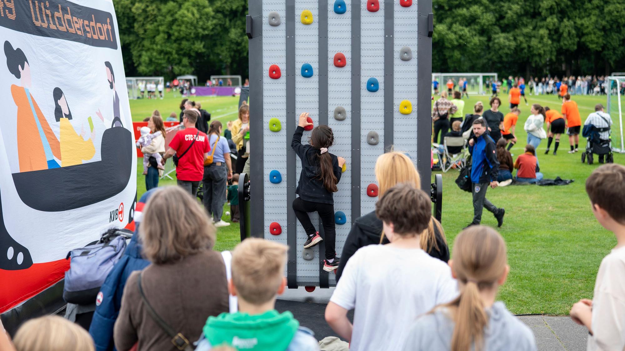 Ein Kind an einer Kletterwand, dahinter eine Fußballwiese - beim Come Together Cup.