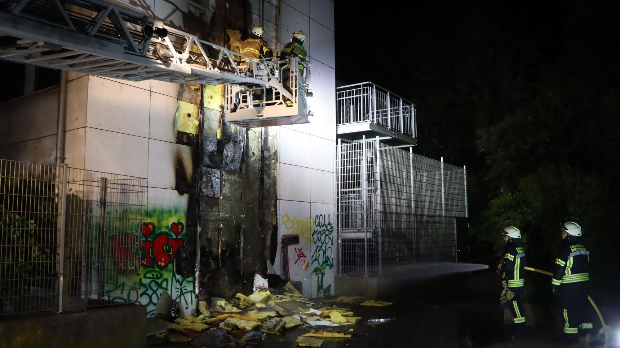 Zu sehen sind Feuerwehrleute vor der vom Feuer beschädigten Fassade.
