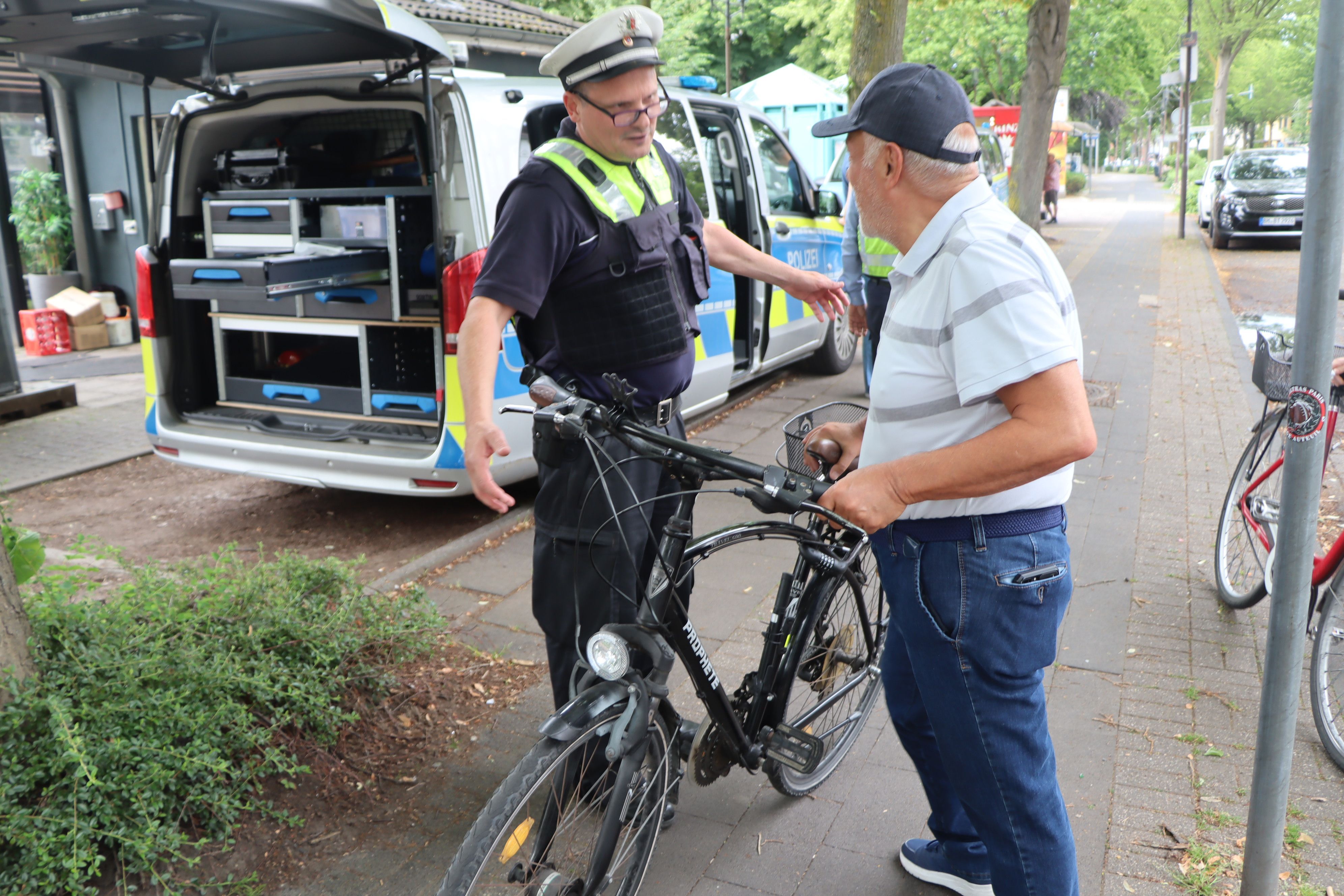 Das Bild zeigt einen Polizeibeamten und einen Fahrradfahrer.