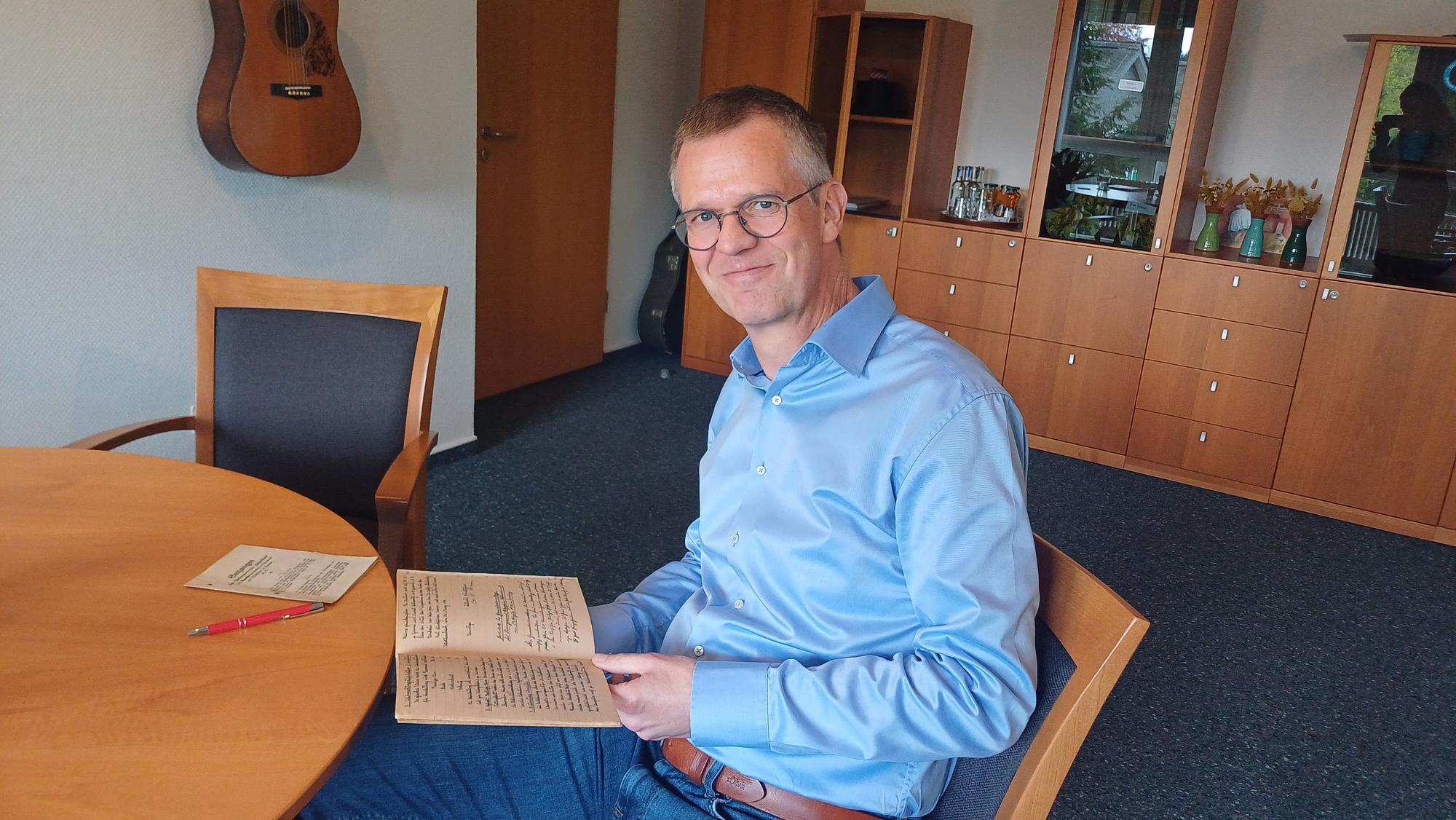 Geschäftsführer Ralf Beyer blättert in Unterlagen zur Historie des Pilgerheims.