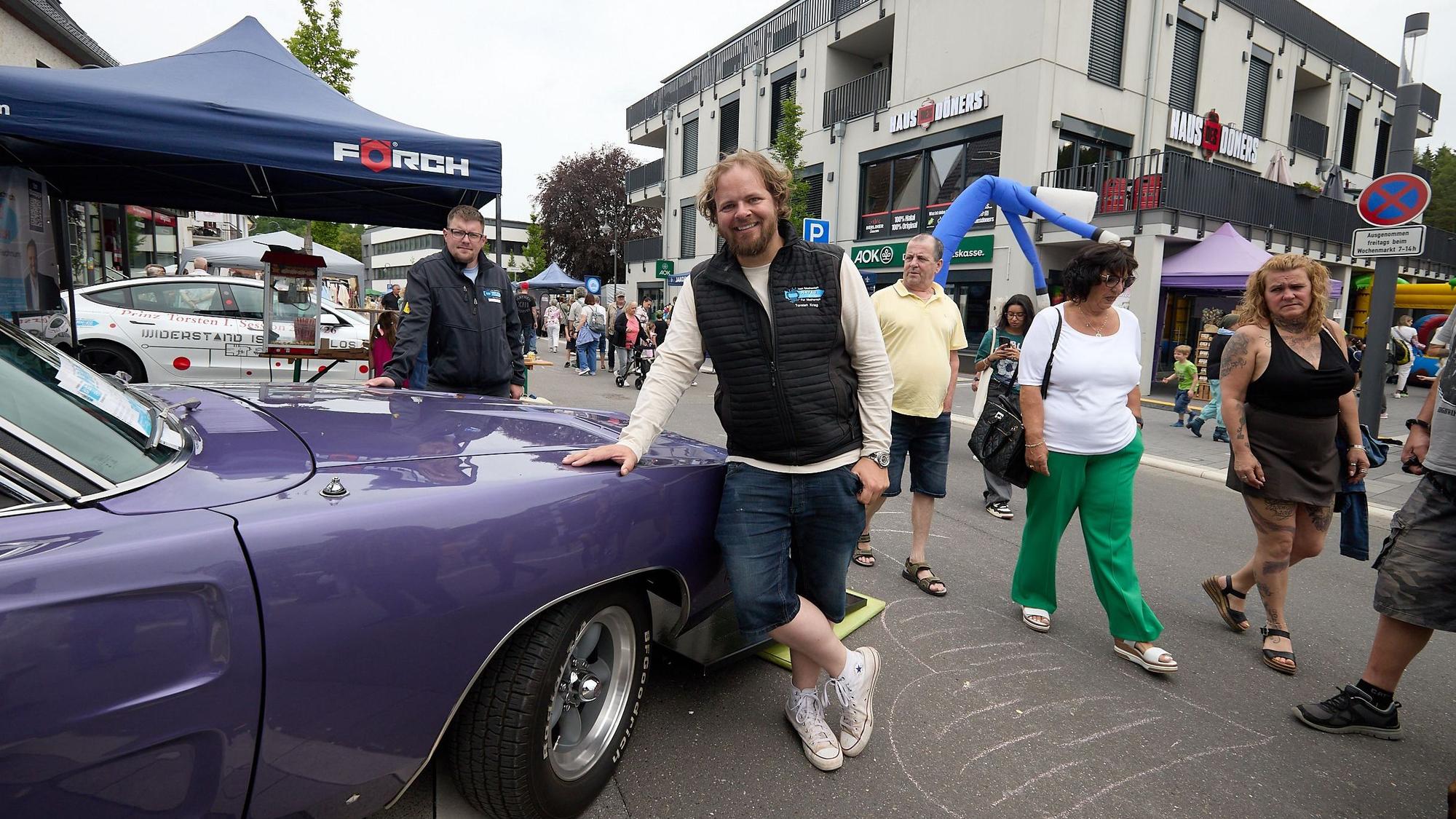 Torsten Krieg und Michael Hamer stehen an einem Auto, im Hintergrund sind Besucher der Frühjahrsschau zu sehen.
