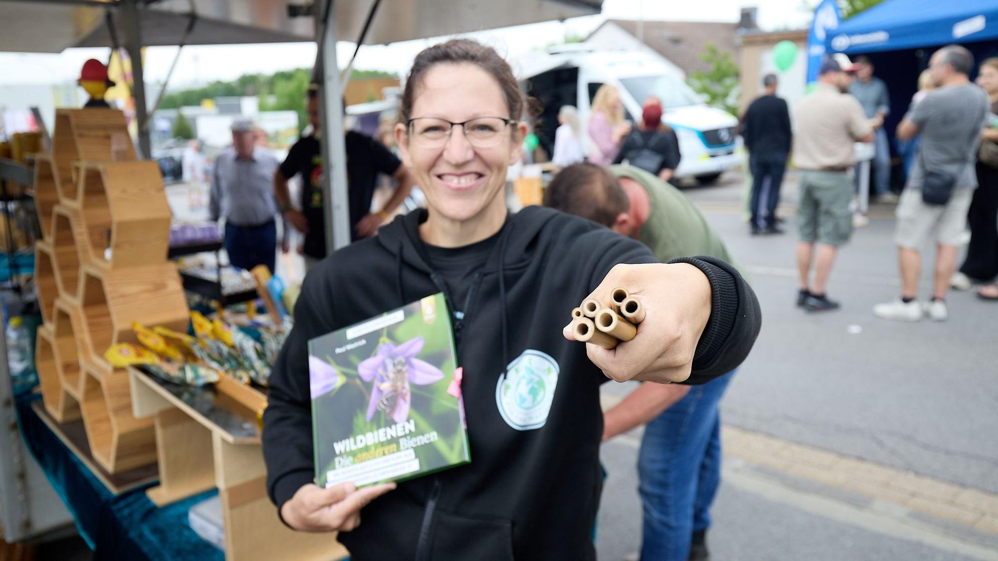Sonja Walter zeigt Bambusröhren vor ihrem Stand mit Imkereiprodukten.