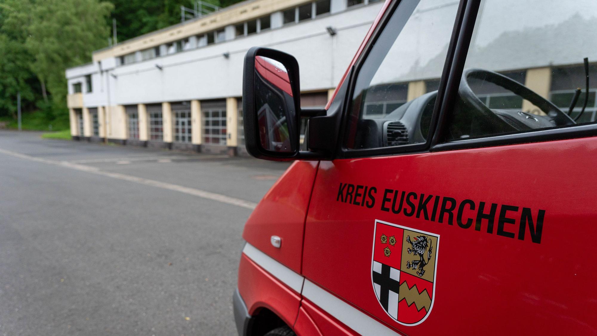 Im Hintergrund ist das Brandschutzzentrum des Kreises Euskirchen in Schleiden zu sehen, im Vordergrund ein Feuerwehrfahrzeug mit dem Kreis-Wappen und der Aufschrift „Kreis Euskirchen“.