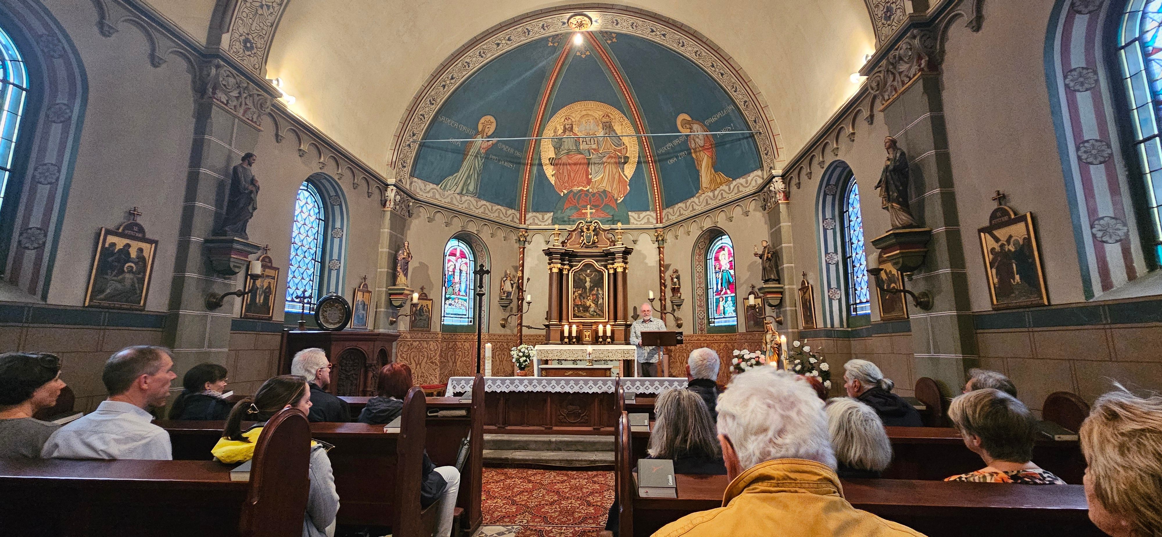 Zu sehen sind Besucherinnen und Besucher in einer Kapelle.