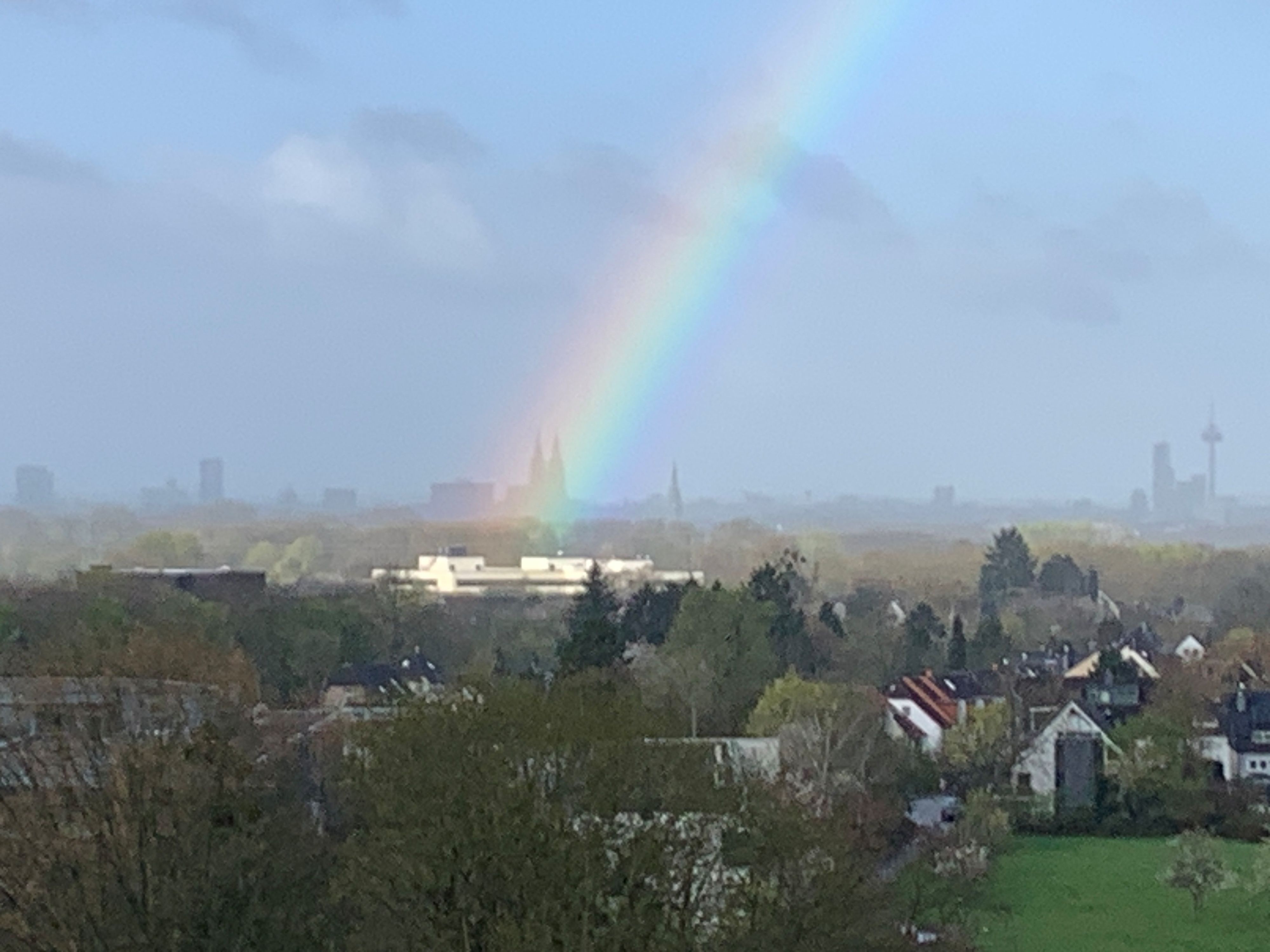 Ein Regenbogen über Köln endet am Kölner Dom.