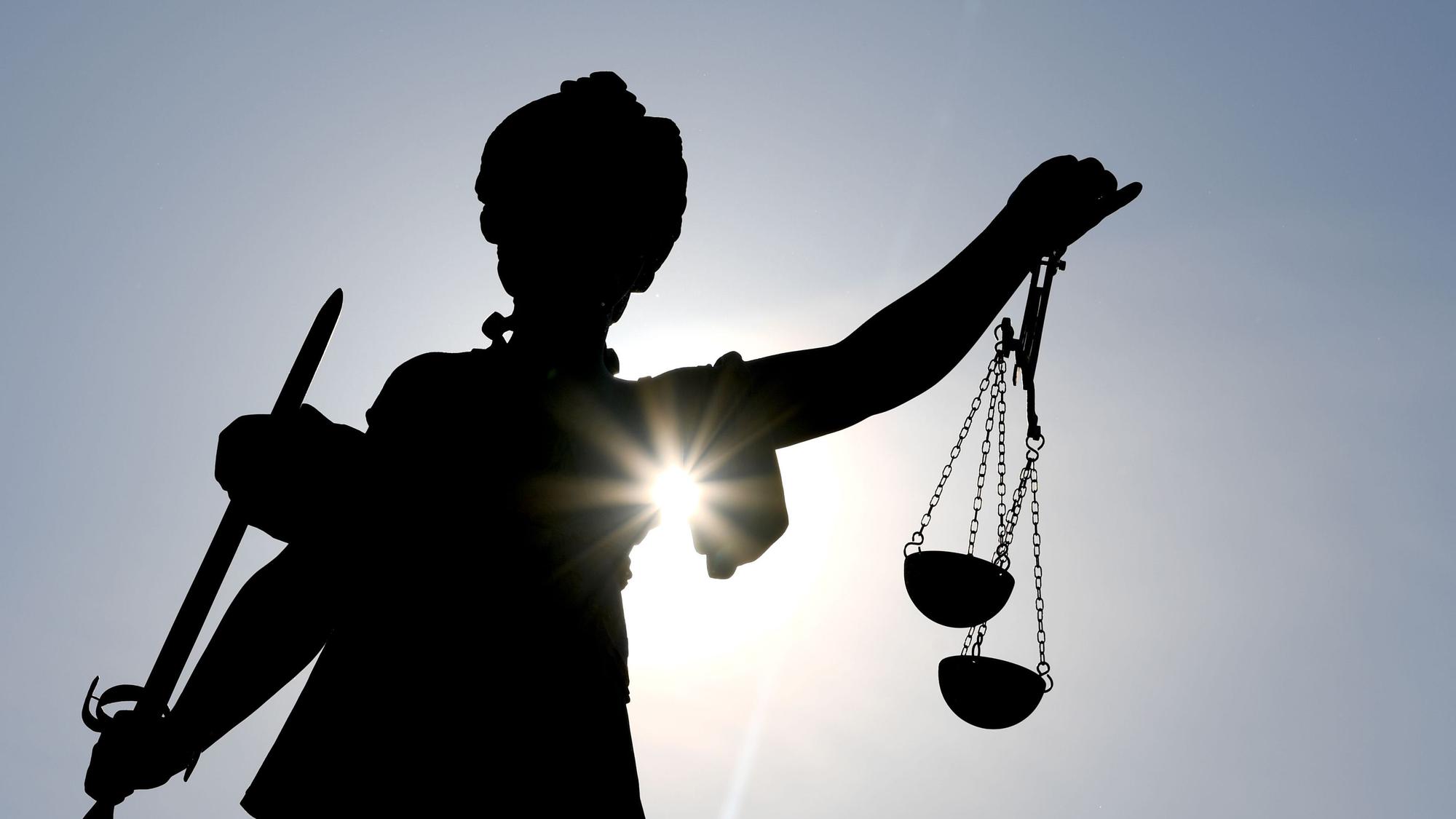 Die Göttin Justitia als Statue im Gegenlicht.