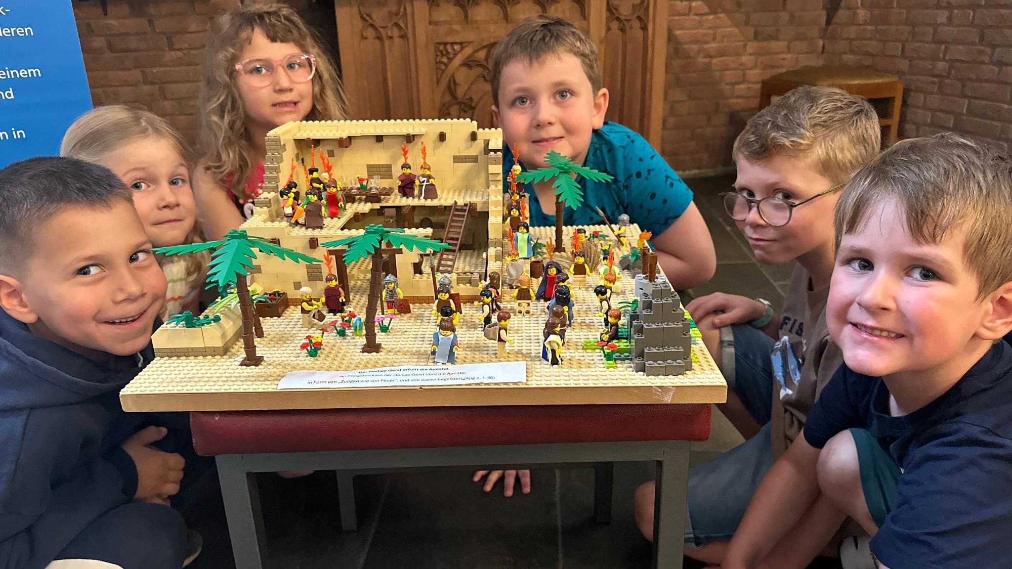 Ganz nah Anschauen erwünscht: Kindergartenkinder an der Station der Ausstellung, die Pfingsten darstellt.