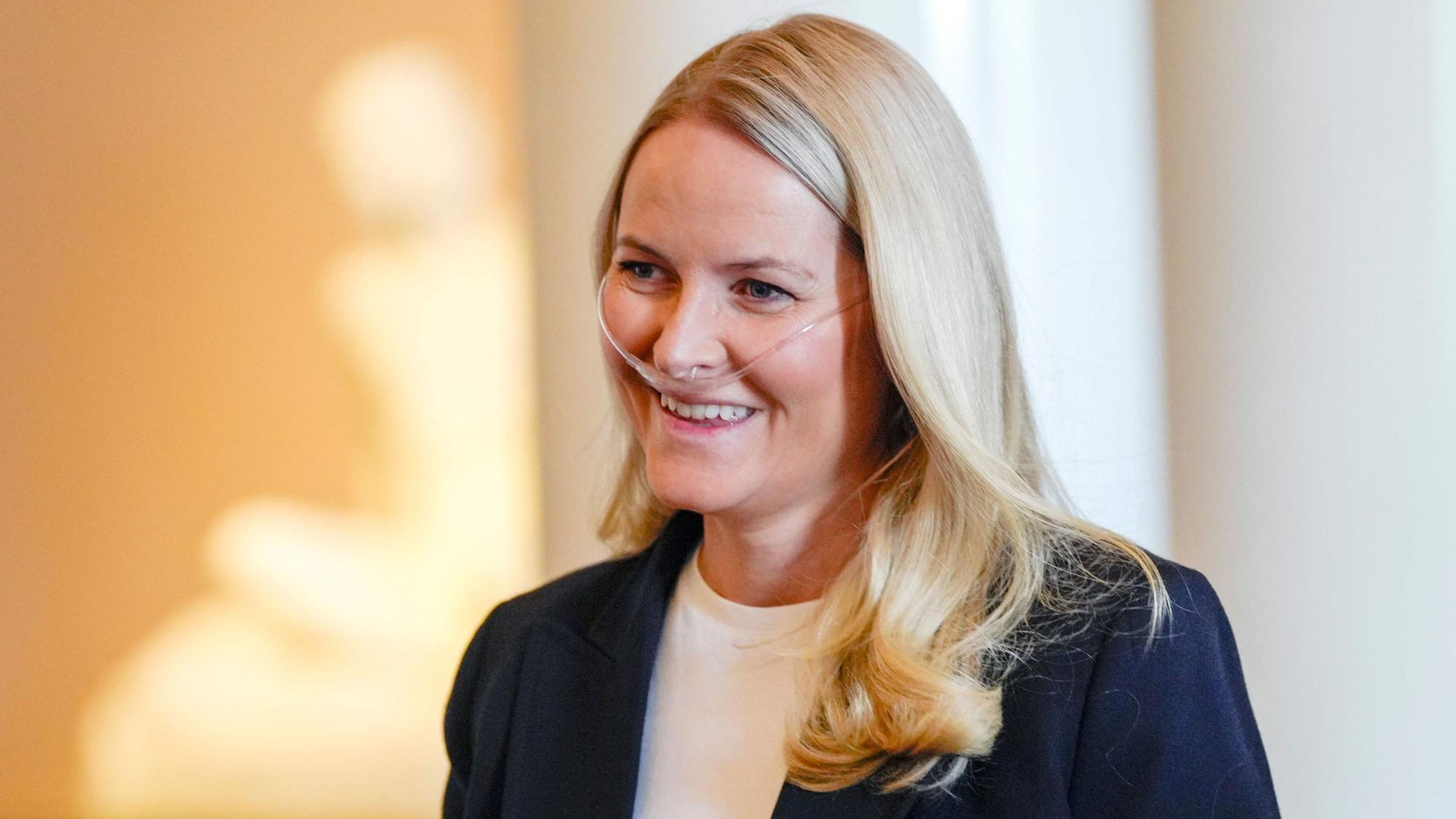 Mette-Marit lächelt mit Sauerstoffgerät.