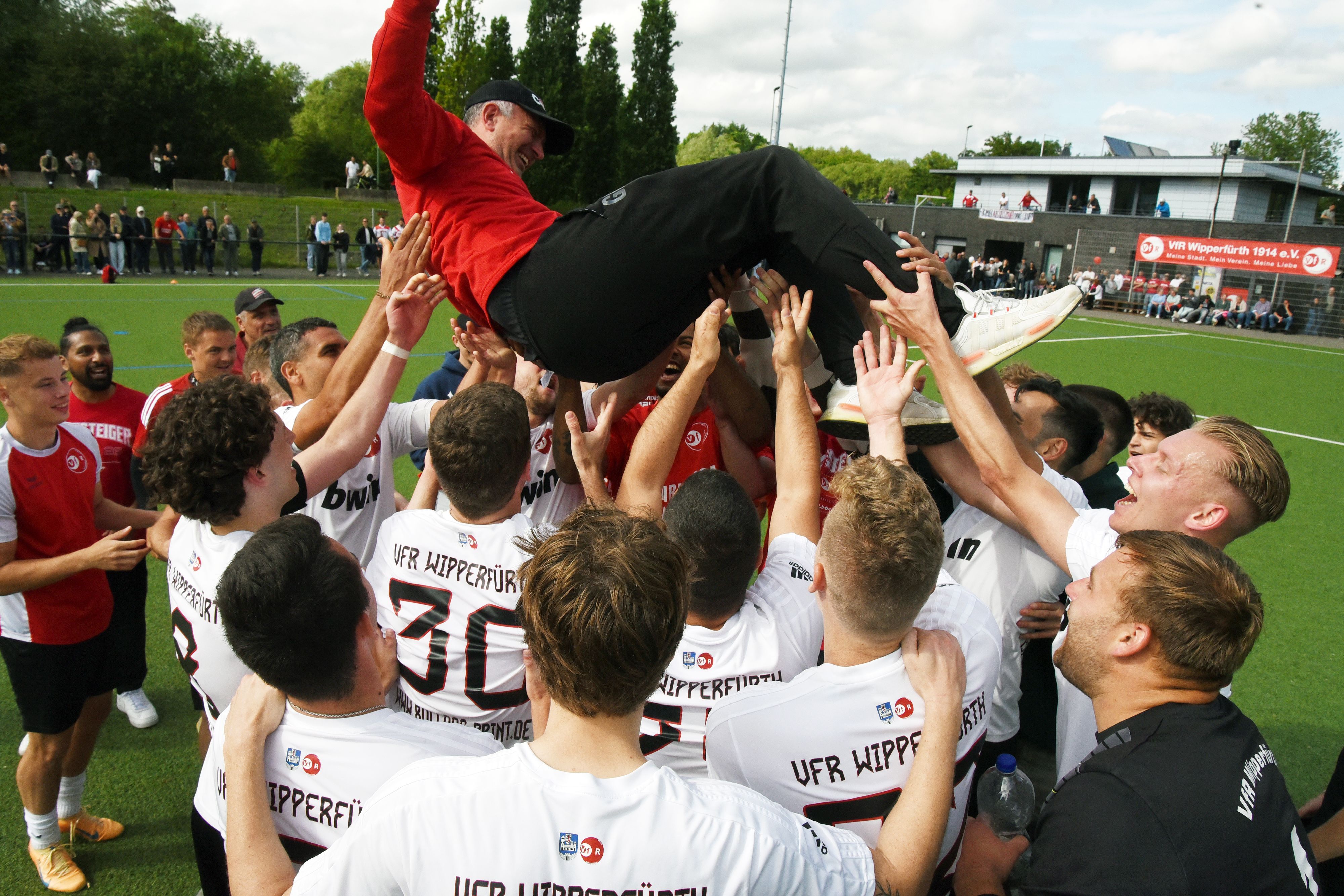 Fußballspieler werfen ihren Trainer in die Luft und feiern ihn.