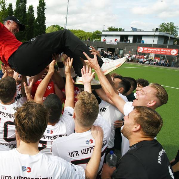 Fußballspieler werfen ihren Trainer in die Luft und feiern ihn.