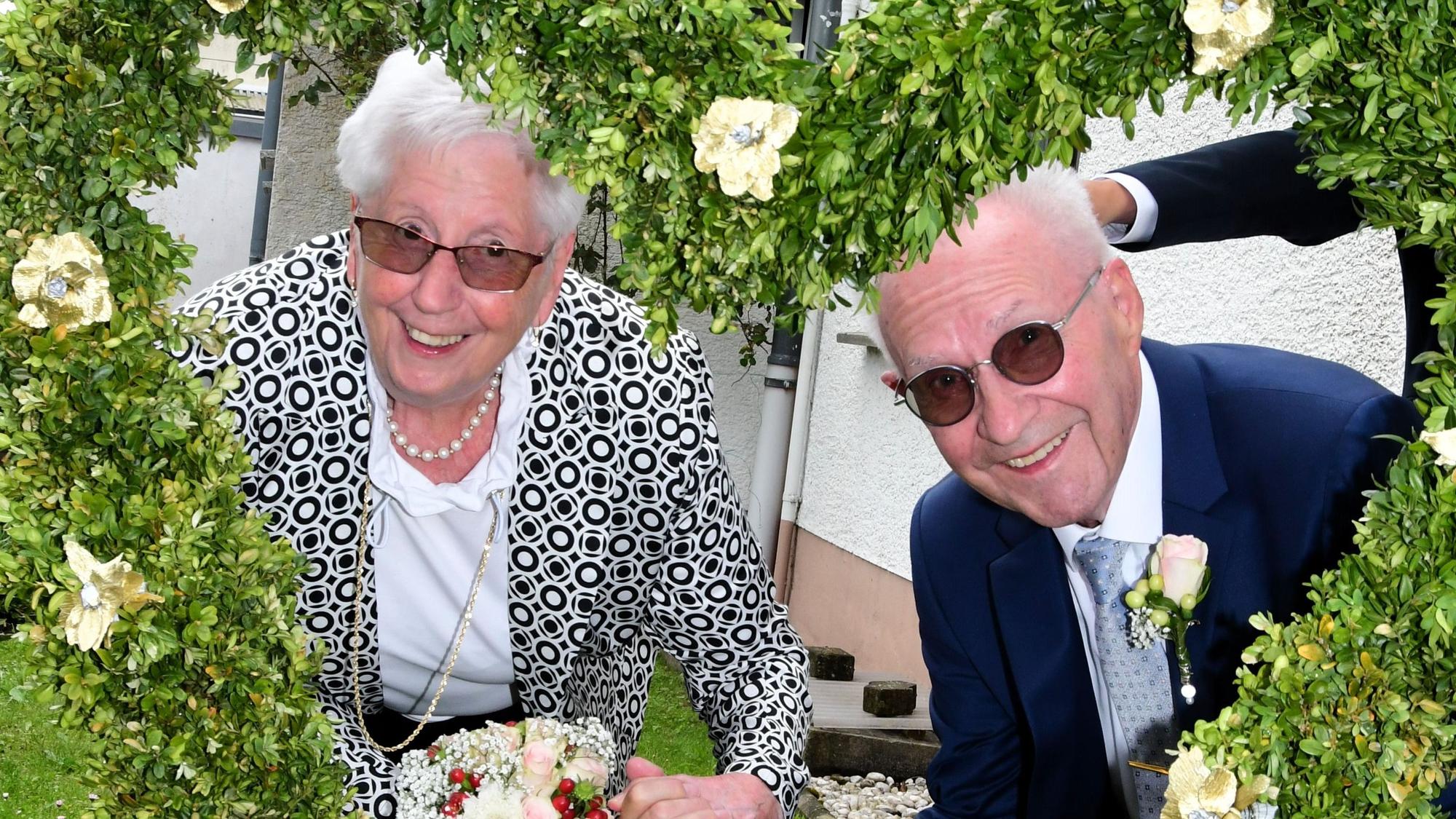Margarete und Ludwig Ginster schauen durch ein Buchsbaum-Herz, das ihre Gäste zur Diamanthochzeit gestaltet haben.