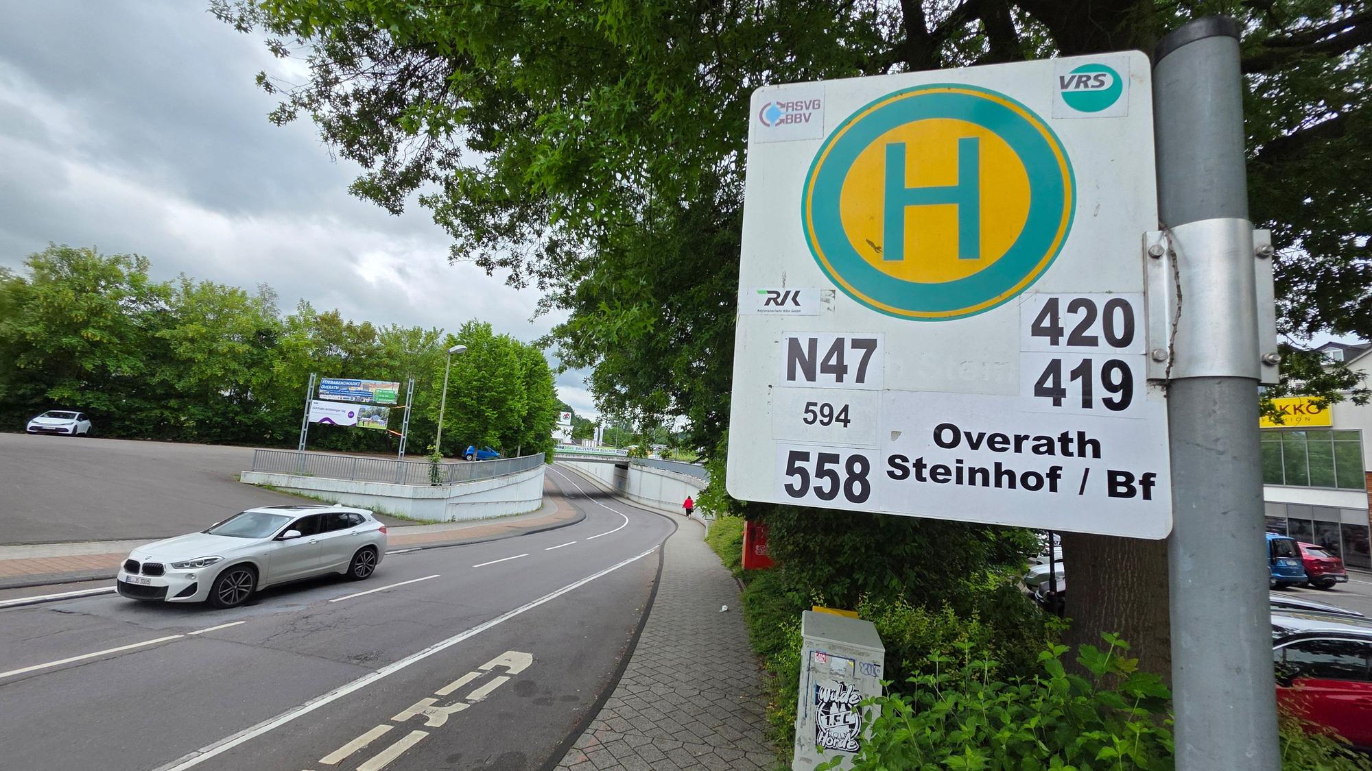 Im Vordergrund ist ein Bushaltestellenschild unter anderem der Buslinie 419 zu sehen, im Hintergrund die Propsteistraße in Overath.