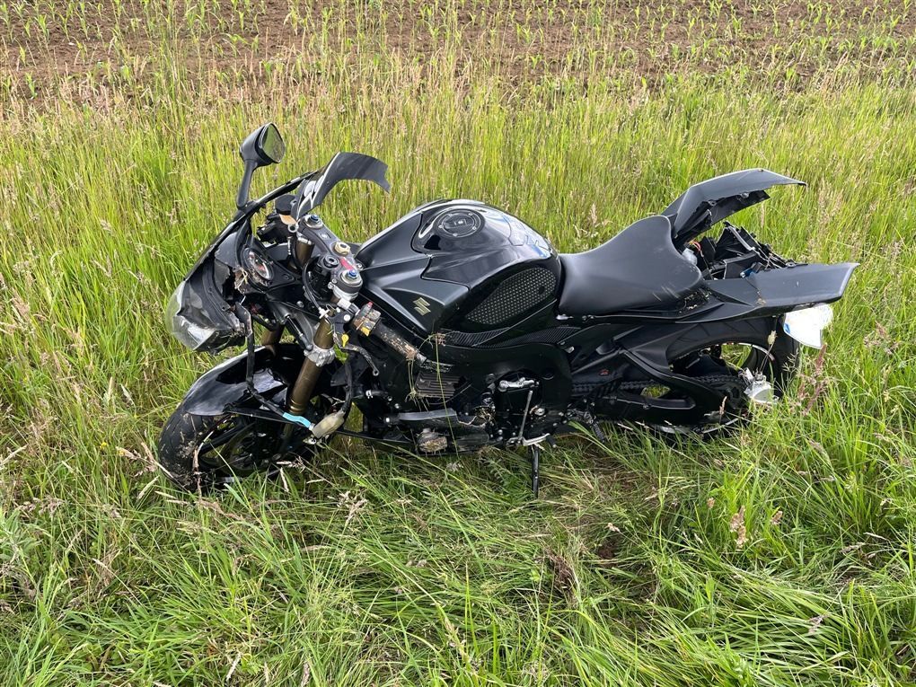 Ein Motorradfahrer liegt nach einem Sturz neben seiner Maschine.