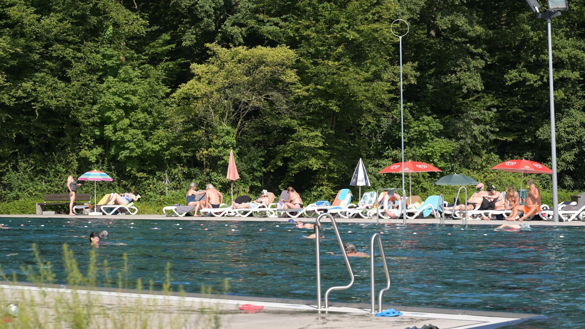 Im Vordergrund ist das Schwimmerbecken, im Hintergrund liegen Leute auf Liegen.