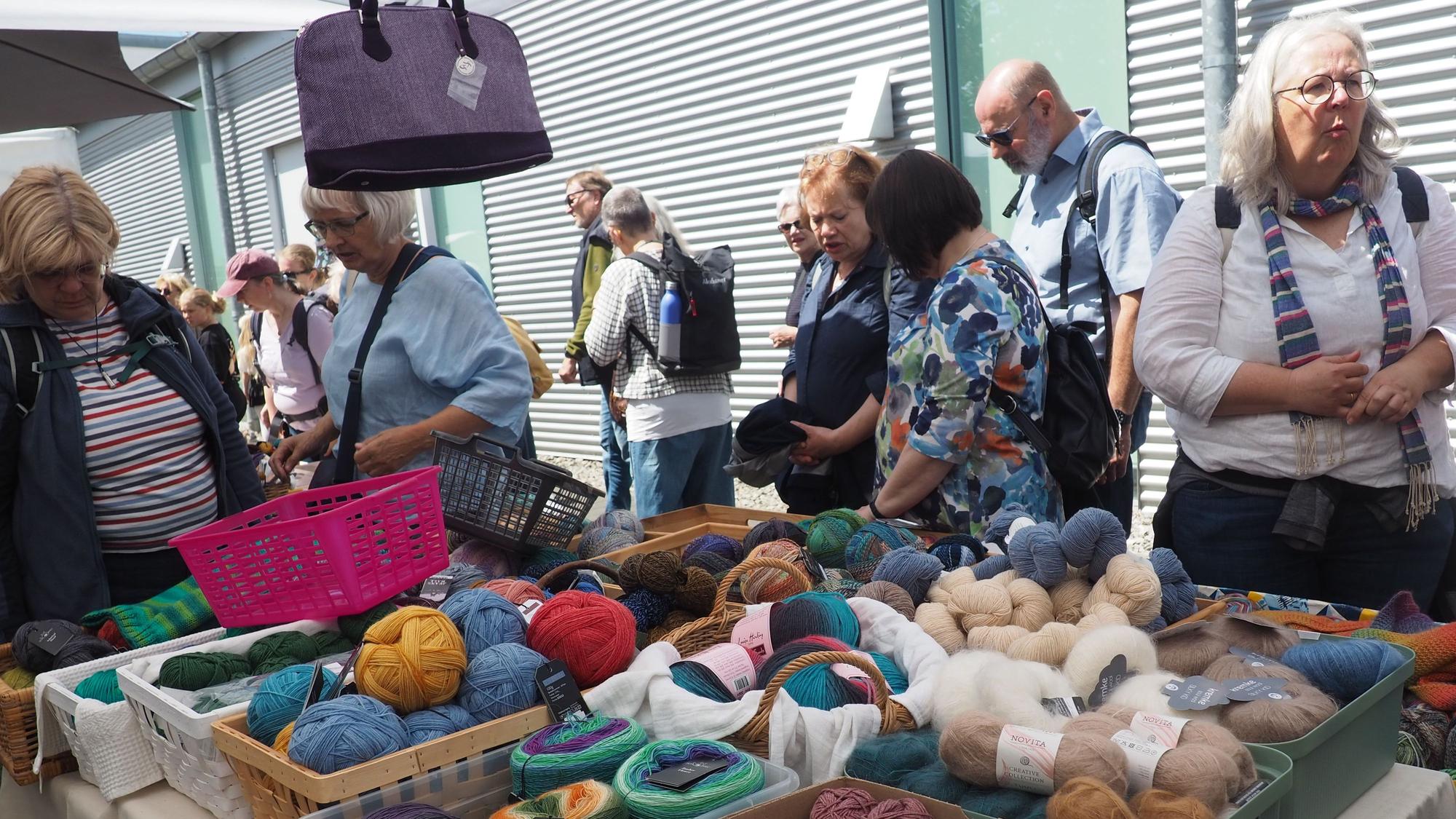 Menschen stehen vor einem Stand mit Wolle.