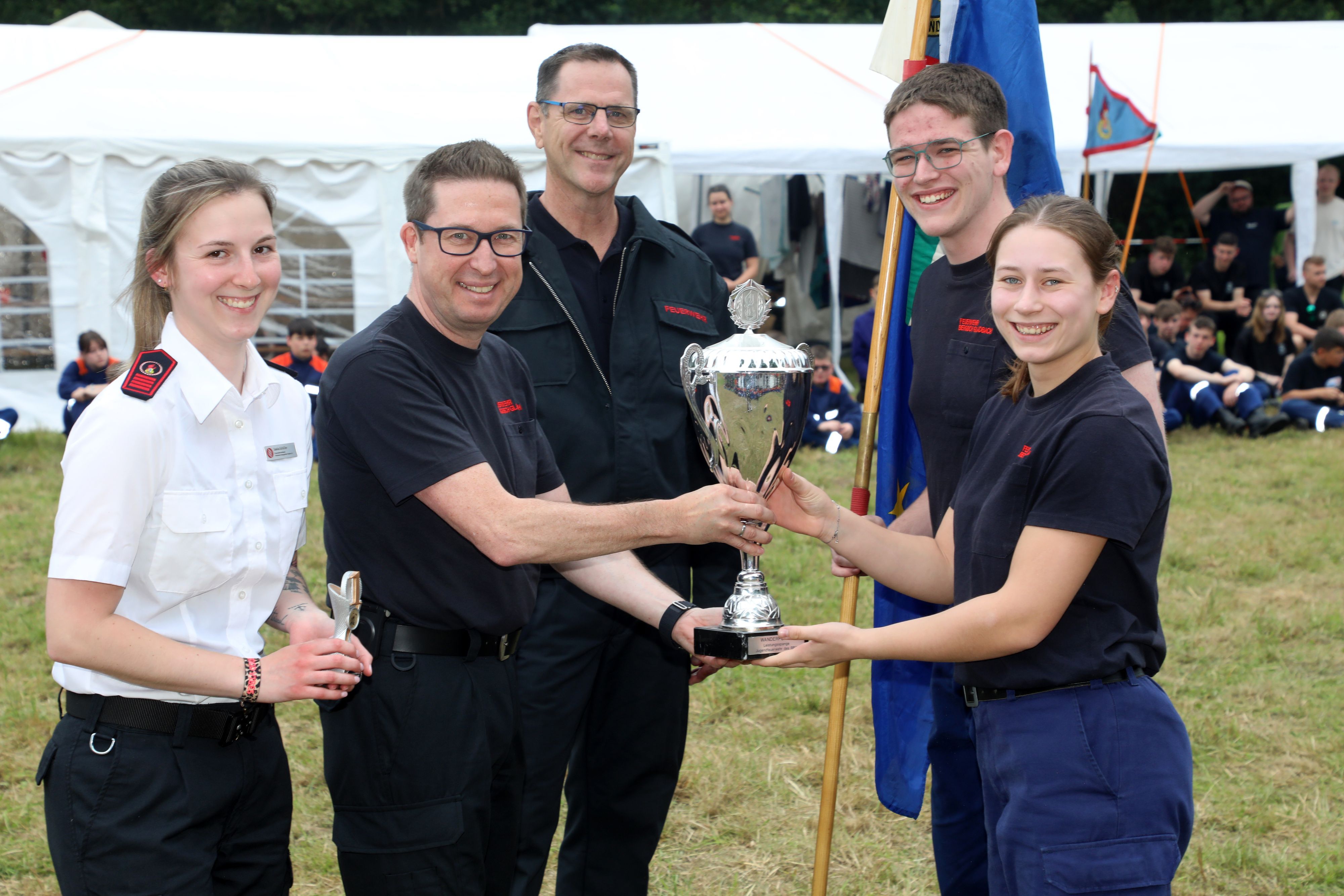 Frank Haag vom Kreisfeuerwehrverband überreicht den Pokal für die Sieger beim Leistungsspange-Wettbewerb zusammen mit Saskia Schüller (l.) und Feuerwehrkreisverbandschef Jörg Köhler an Marie Pütz von der Jugendfeuerwehr Bergisch Gladbach-Paffrath/Hand.