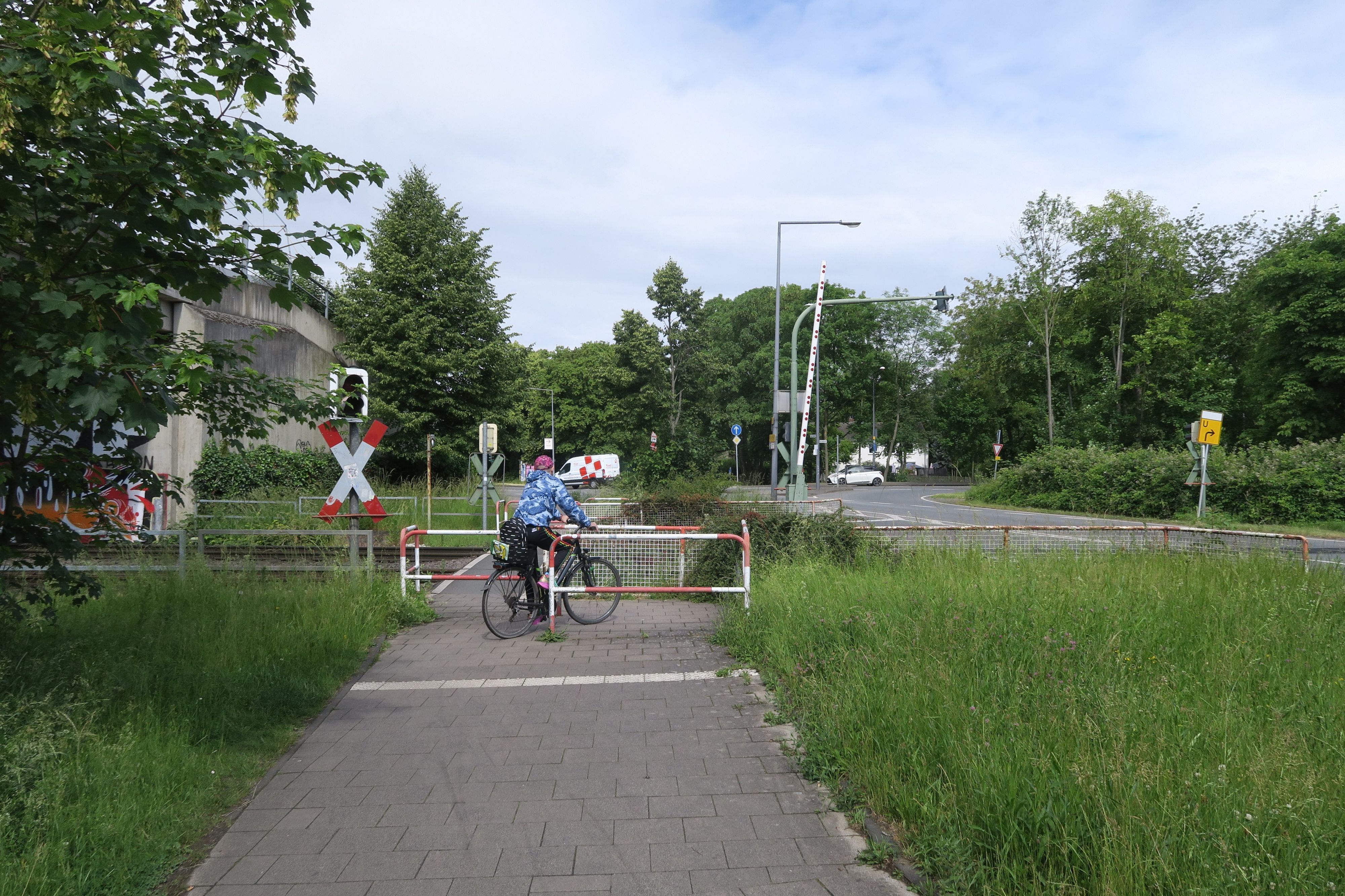 Ein Radfahrer bewältigt das Drängelgitter unmittelbar vor einem Bahnübergang.