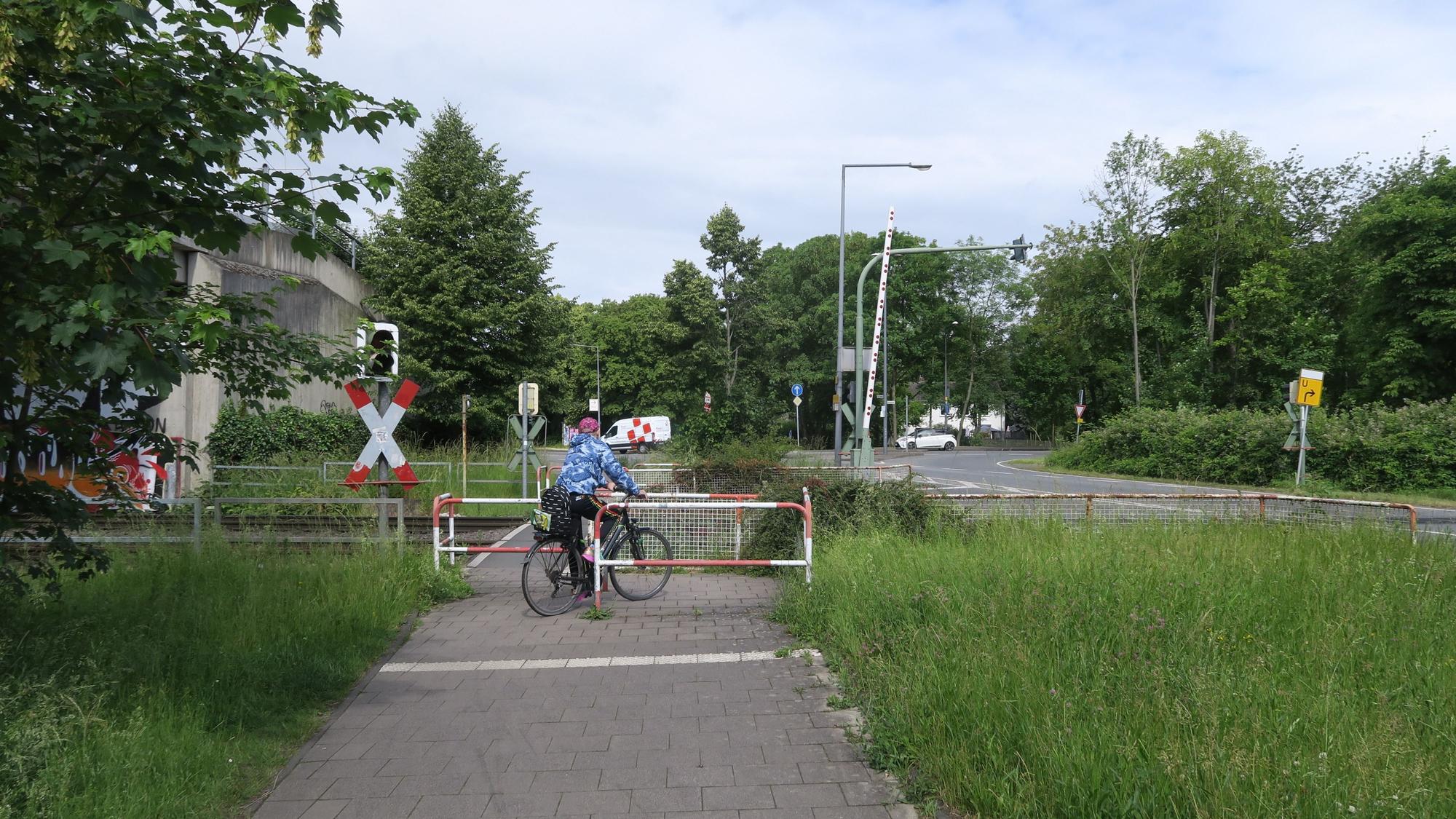 Ein Radfahrer bewältigt das Drängelgitter unmittelbar vor einem Bahnübergang.
