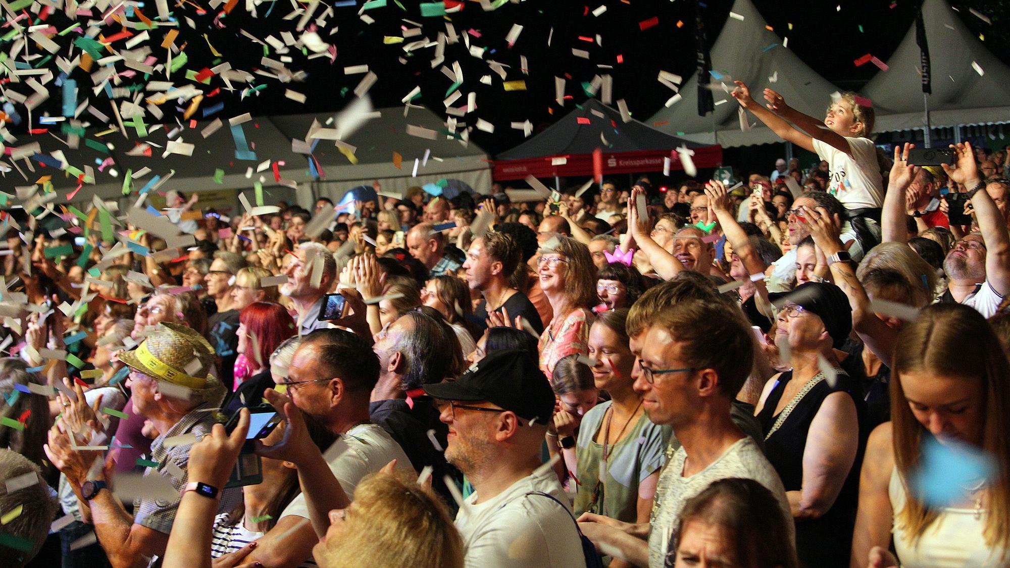 Zu sehen sind Musikfans, über denen eine Konfettikanone gezündet wurde.