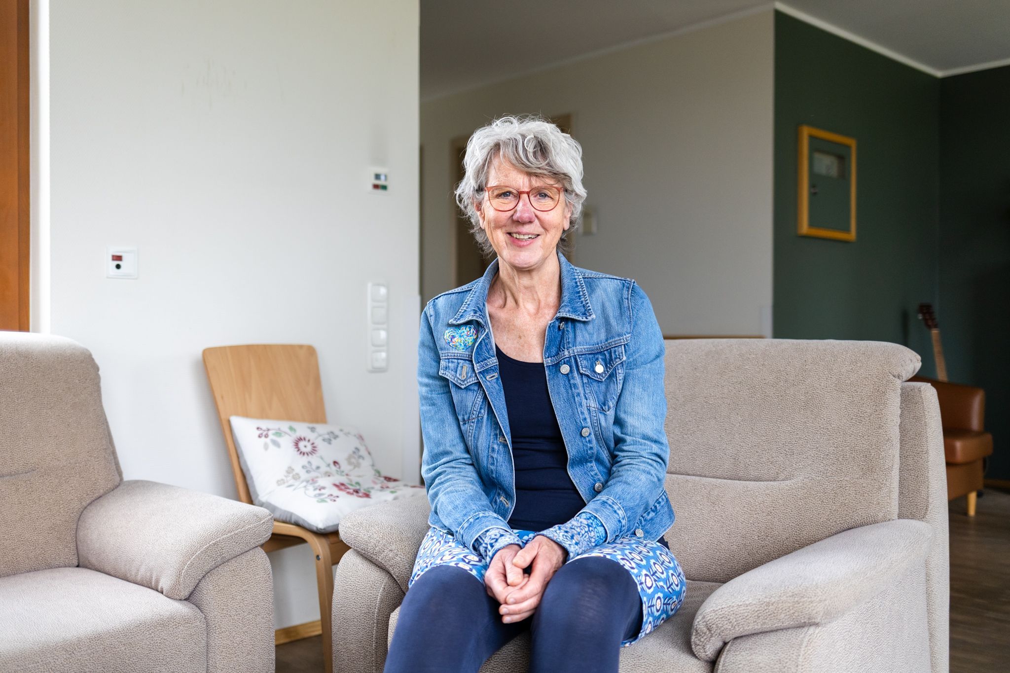 Eine Frau in Jeansjacke lächelt in die Kamera.