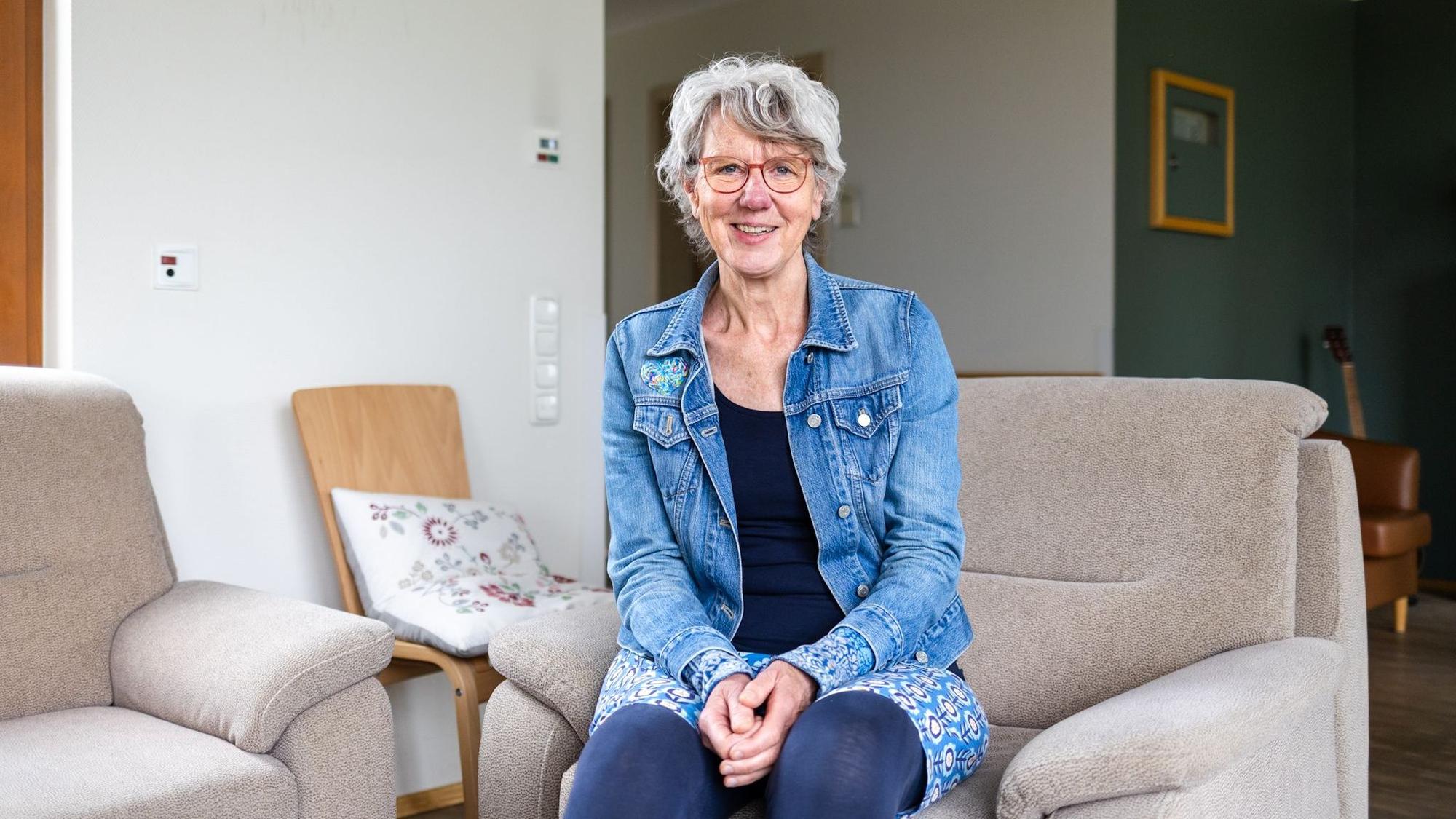Eine Frau in Jeansjacke lächelt in die Kamera.