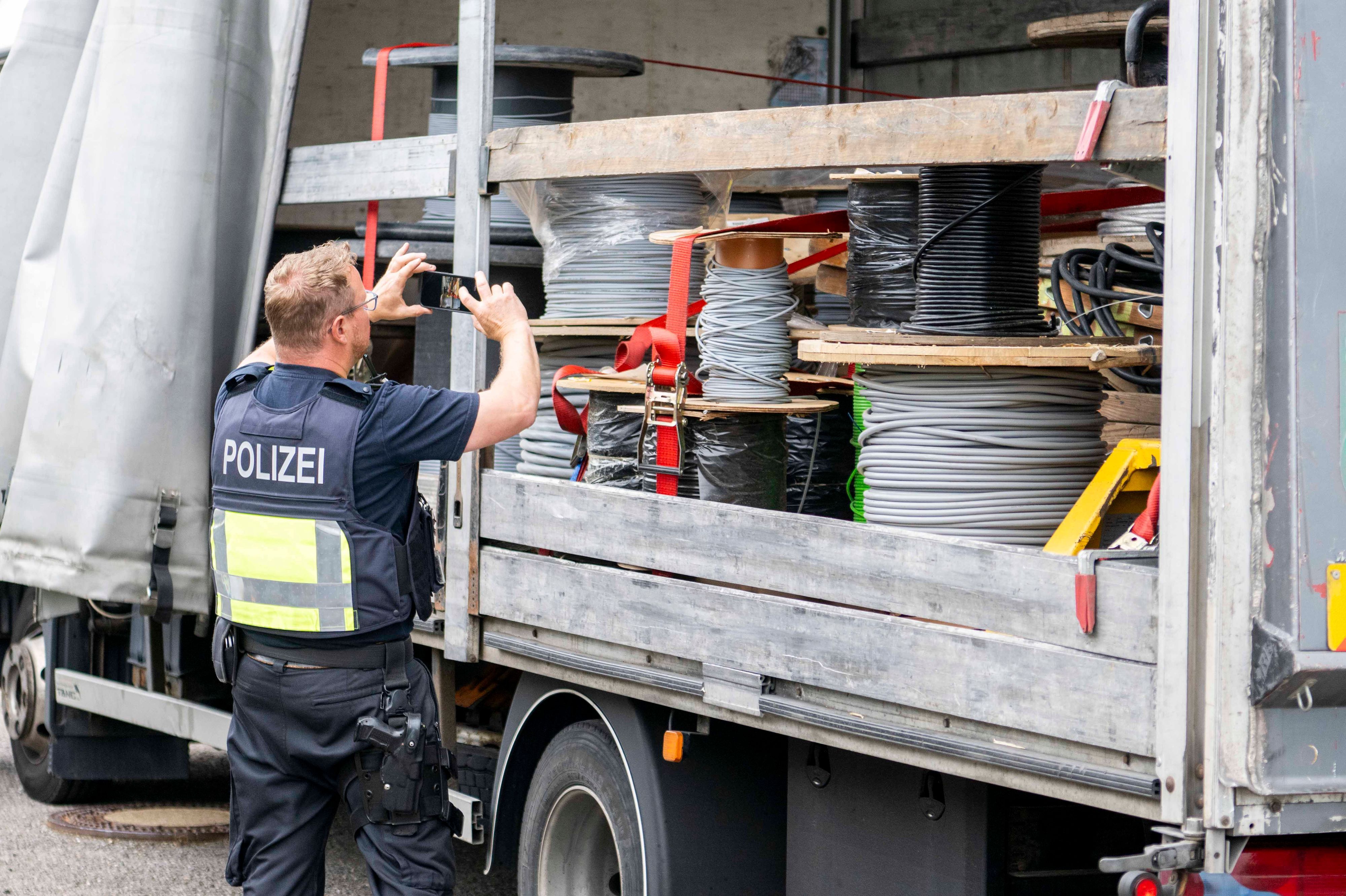 Das Bild zeigt einen Polizeibeamten, der mithilfe eines Handys ein Foto von der Ladung auf einem Lastwagen macht.