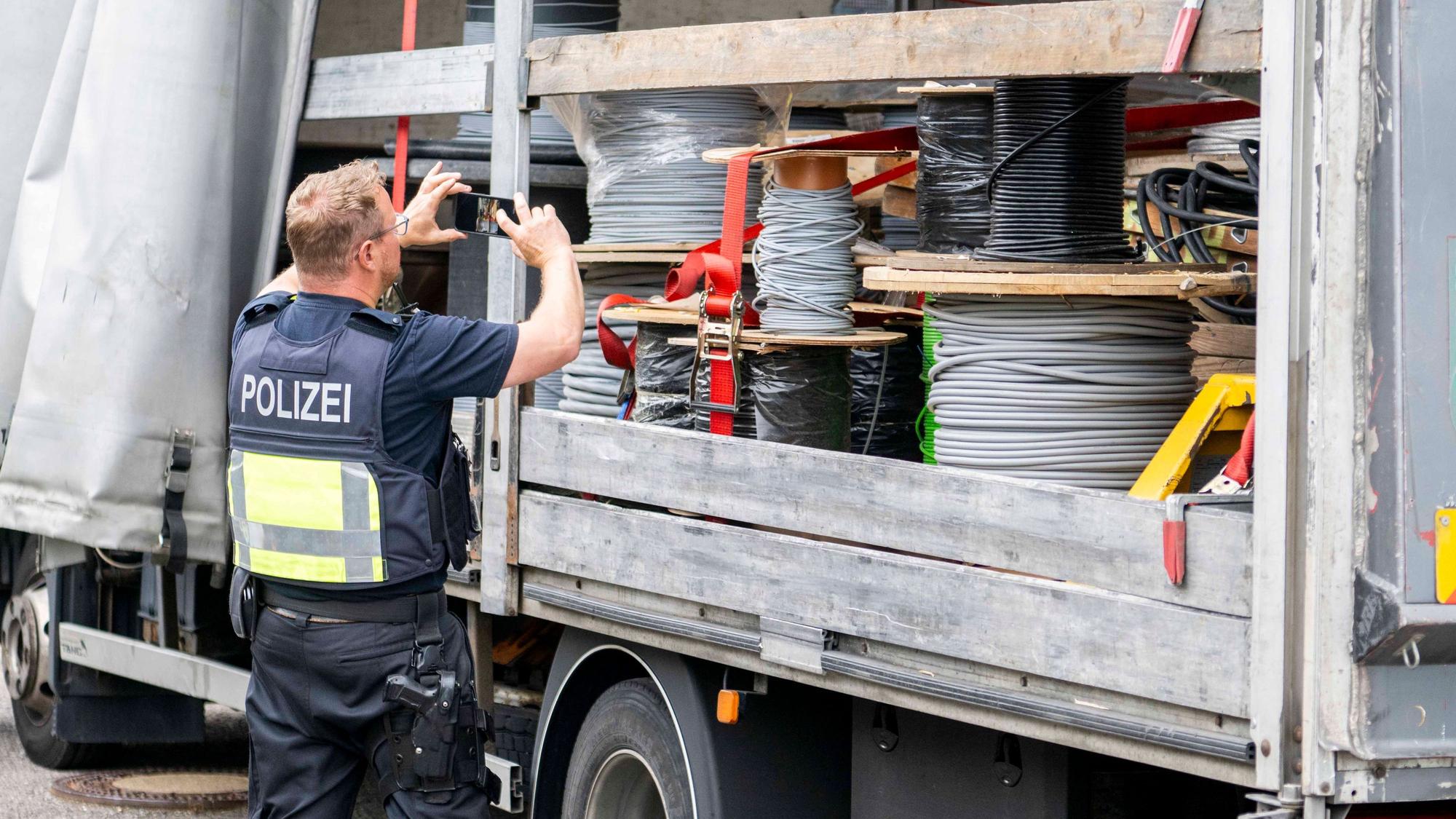 Das Bild zeigt einen Polizeibeamten, der mithilfe eines Handys ein Foto von der Ladung auf einem Lastwagen macht.