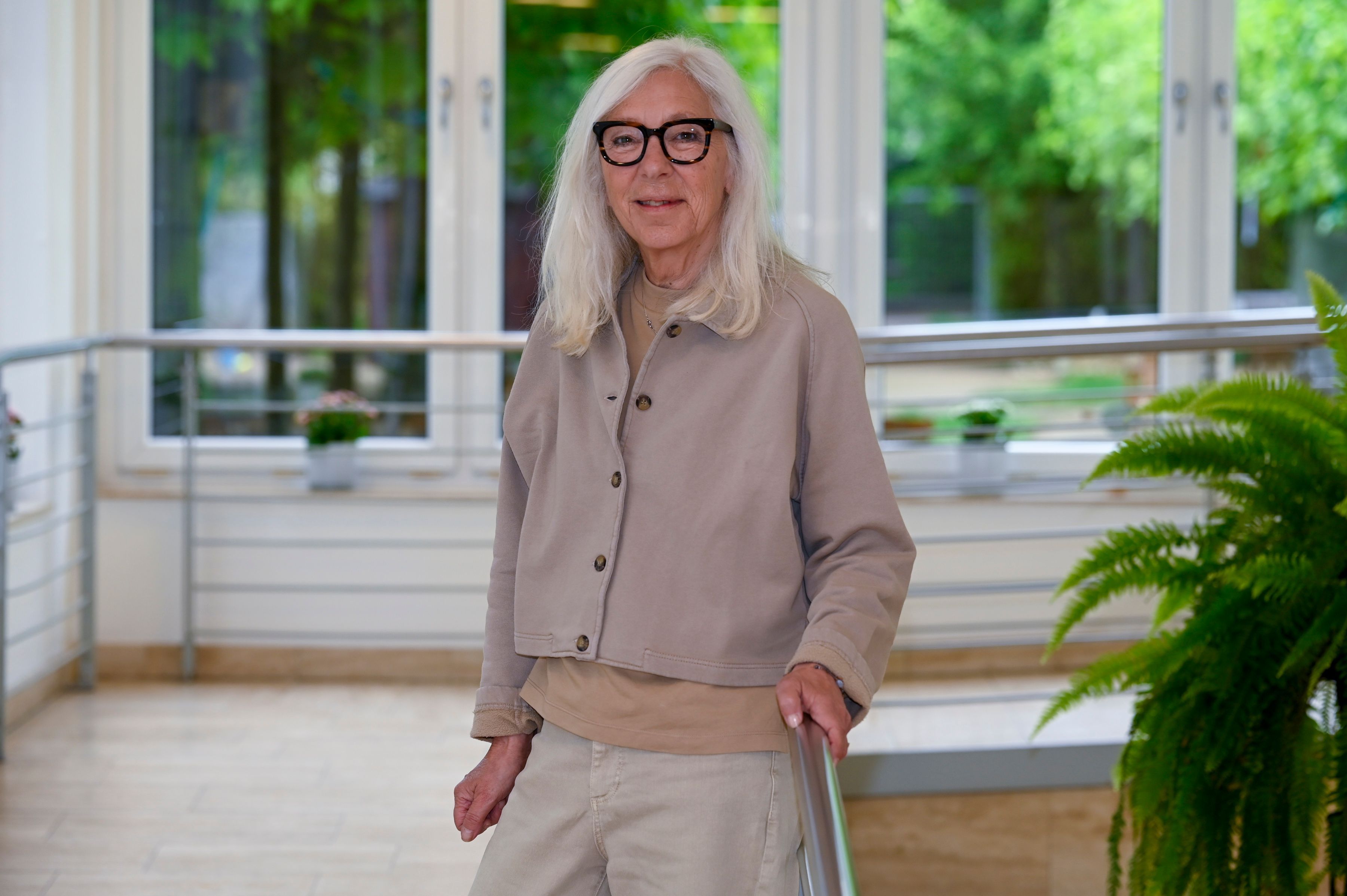 Eine Frau mit weißen Haaren und Brille lächelt in die Kamera.