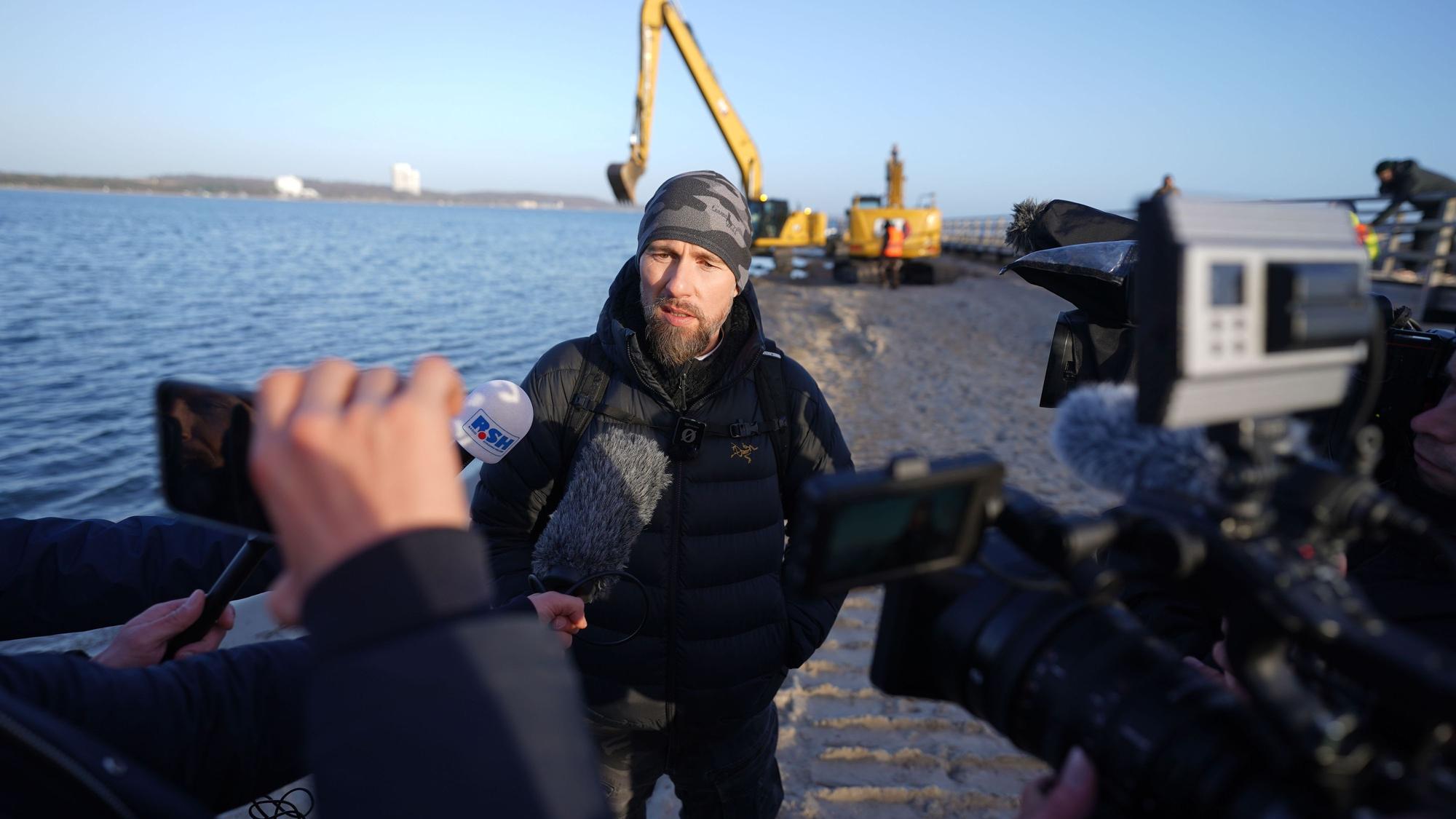 Robert Marc Lehmann, Meeresbiologe, spricht mit den Medien am Strand, wo in der Nähe der gestrandete Buckelwal im Wasser gelegen hatte.
