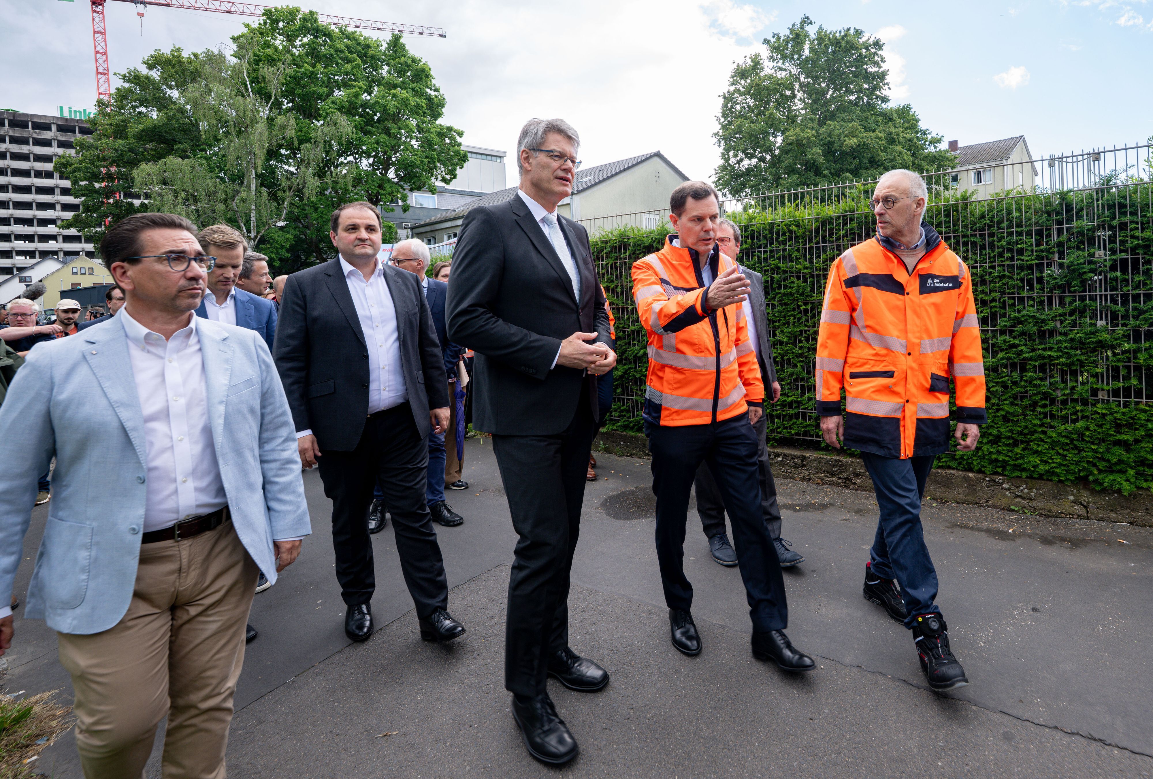 Bundesverkehrsminister Patrick Schnieder (CDU, M) wird vom Vorsitzenden der Geschäftsführung der Autobahnen GmbH, Michael Güntner (2.v.r.) und vom technischen Geschäftsführer Dirk Brandenburger (r) zu gesperrten Bonner Nordbrücke geführt.
