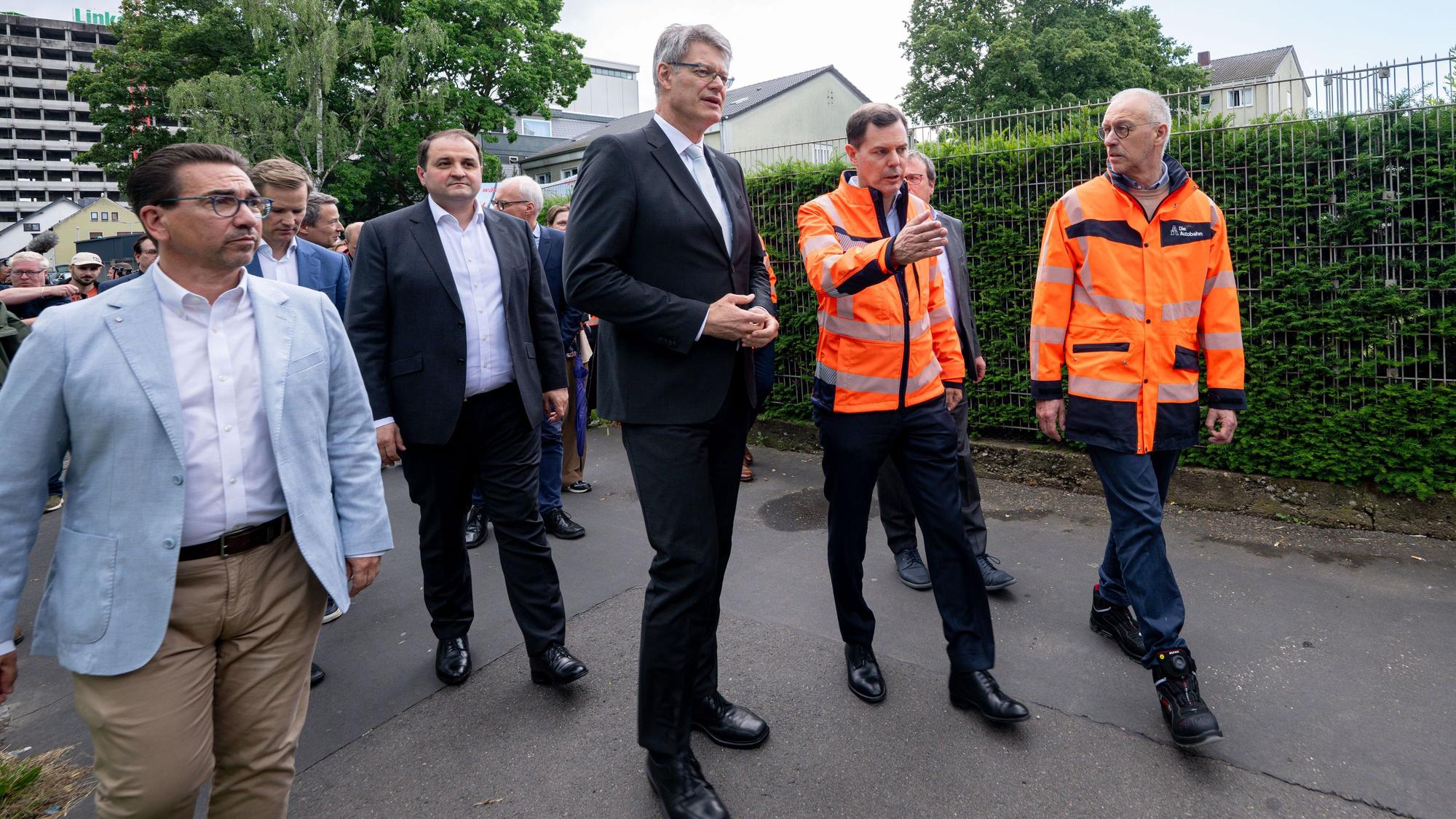 Bundesverkehrsminister Patrick Schnieder (CDU, M) wird vom Vorsitzenden der Geschäftsführung der Autobahnen GmbH, Michael Güntner (2.v.r.) und vom technischen Geschäftsführer Dirk Brandenburger (r) zu gesperrten Bonner Nordbrücke geführt.