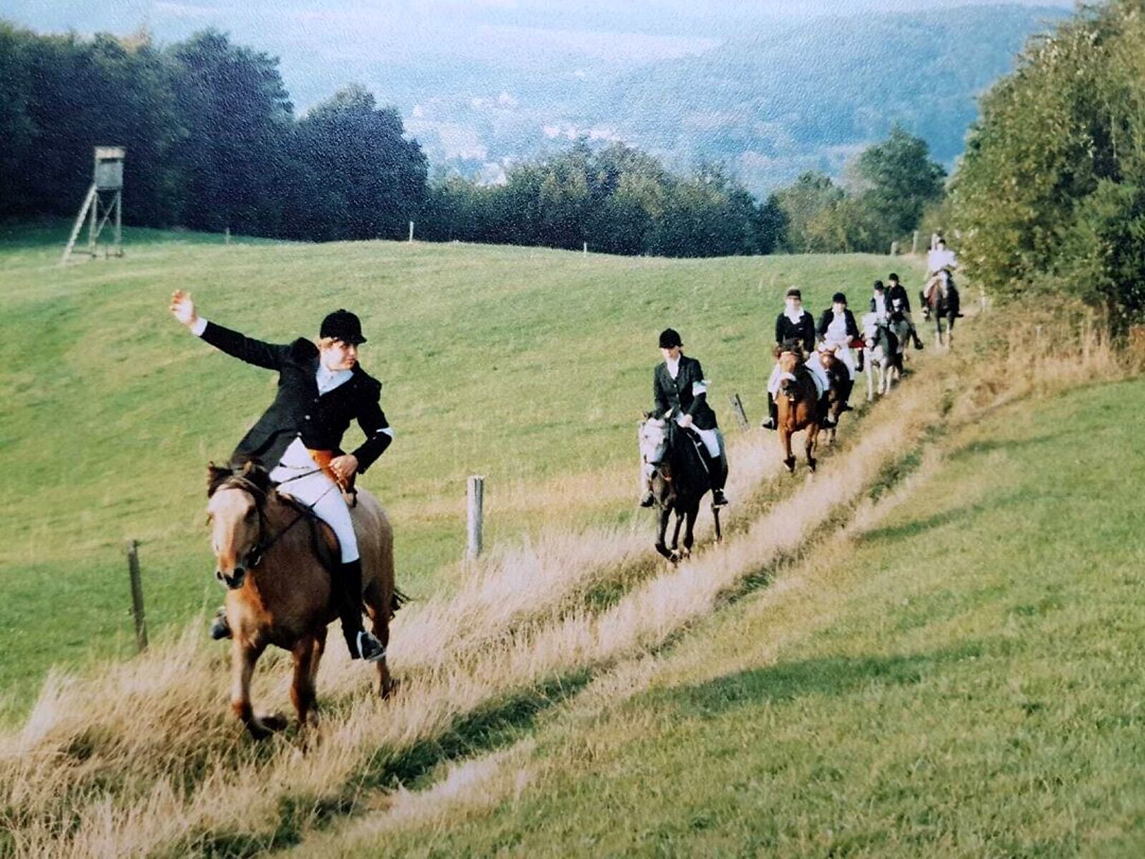 Reiter ziehen in langen Reihen über die Wiesen des Naafbachtals.