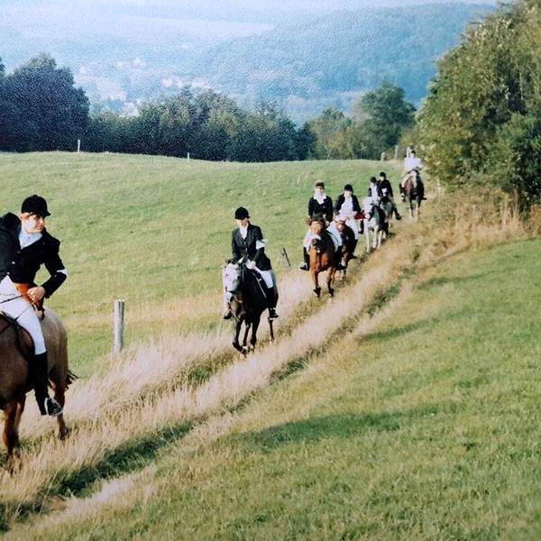 Reiter ziehen in langen Reihen über die Wiesen des Naafbachtals.