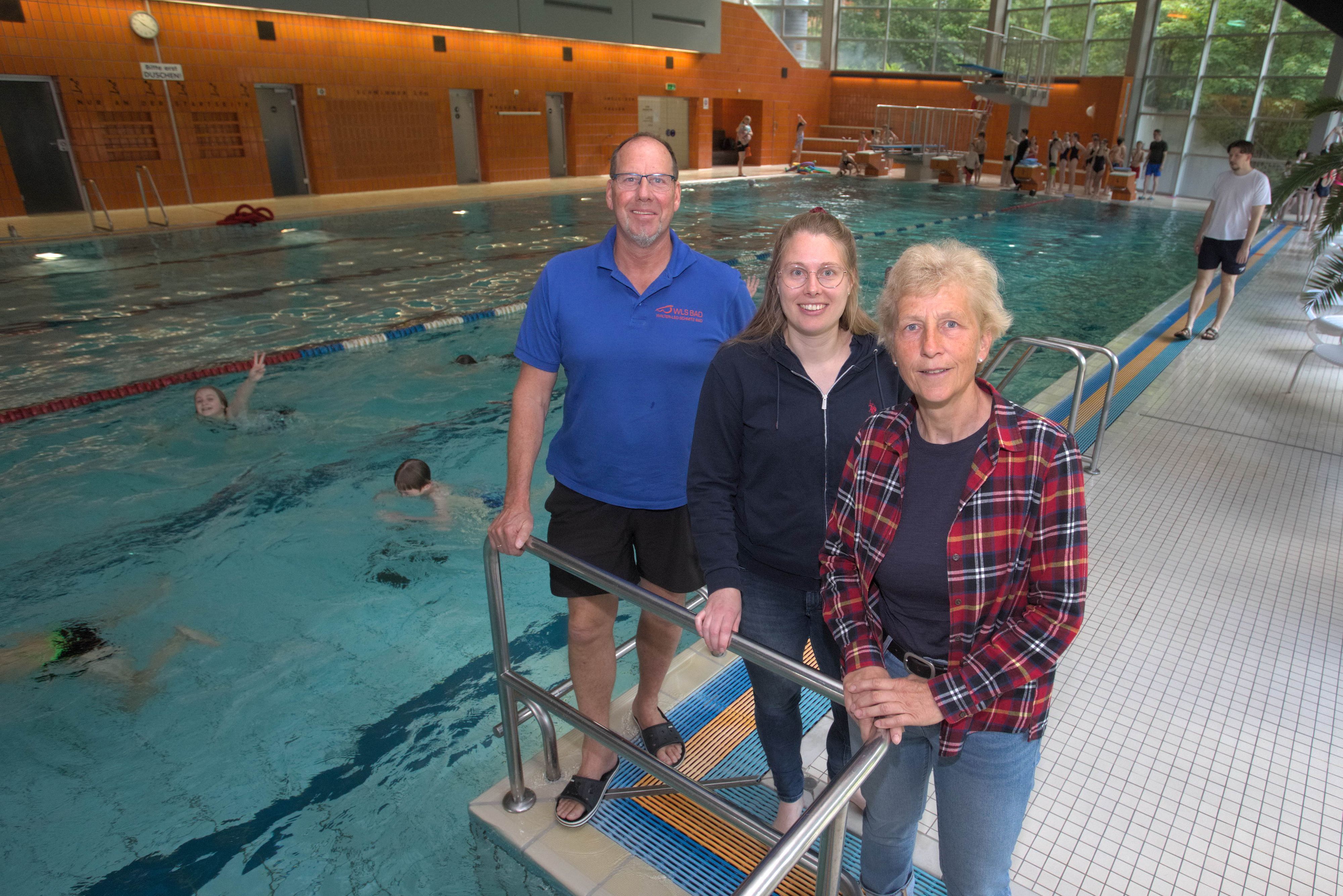 Das Foto zeigt drei Personen und im Hintergrund das große Becken des Wipperfürther Hallenbades.